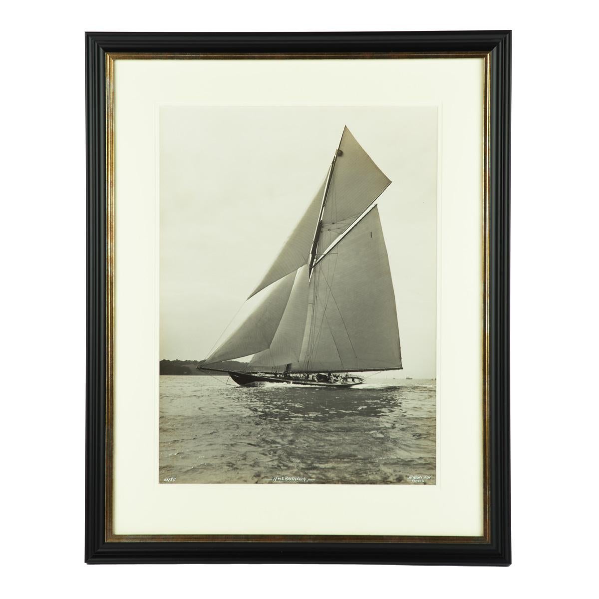 A large silver gelatin photographic print of H.M.Y. Britannia by Beken, on an easterly course on starboard taking, passing Cowes., Inscribed in white ‘H. M. Y. Britannia, No. 10785, Beken & Sons, Cowes’. English, circa 1930.

