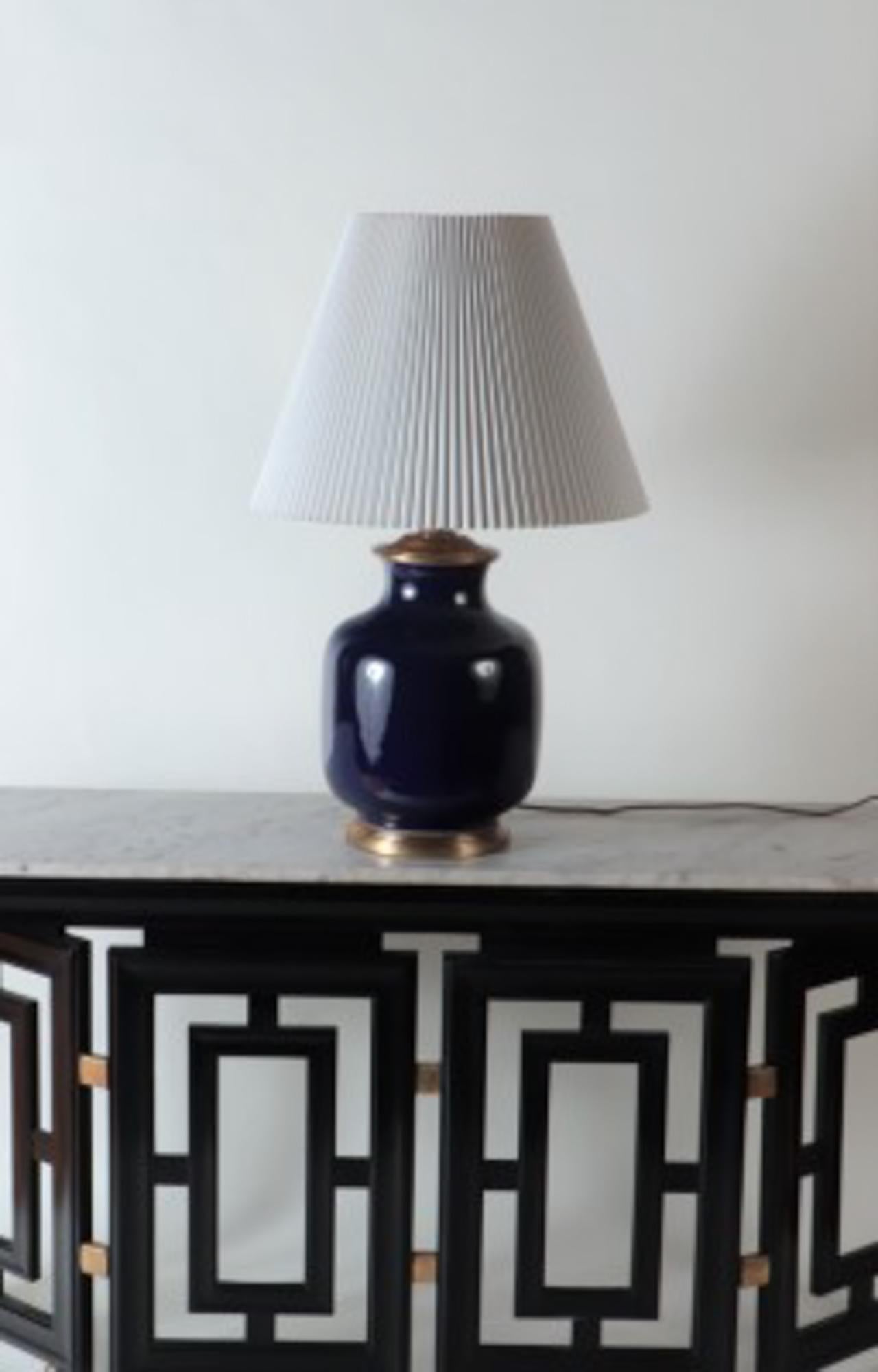 Une grande lampe de table simple en porcelaine bleue de forme balustre, avec base dorée. La quincaillerie en finition antique comprend des douilles doubles avec des chaînes à tirer on/off, et un cordon recouvert de tissu brun.