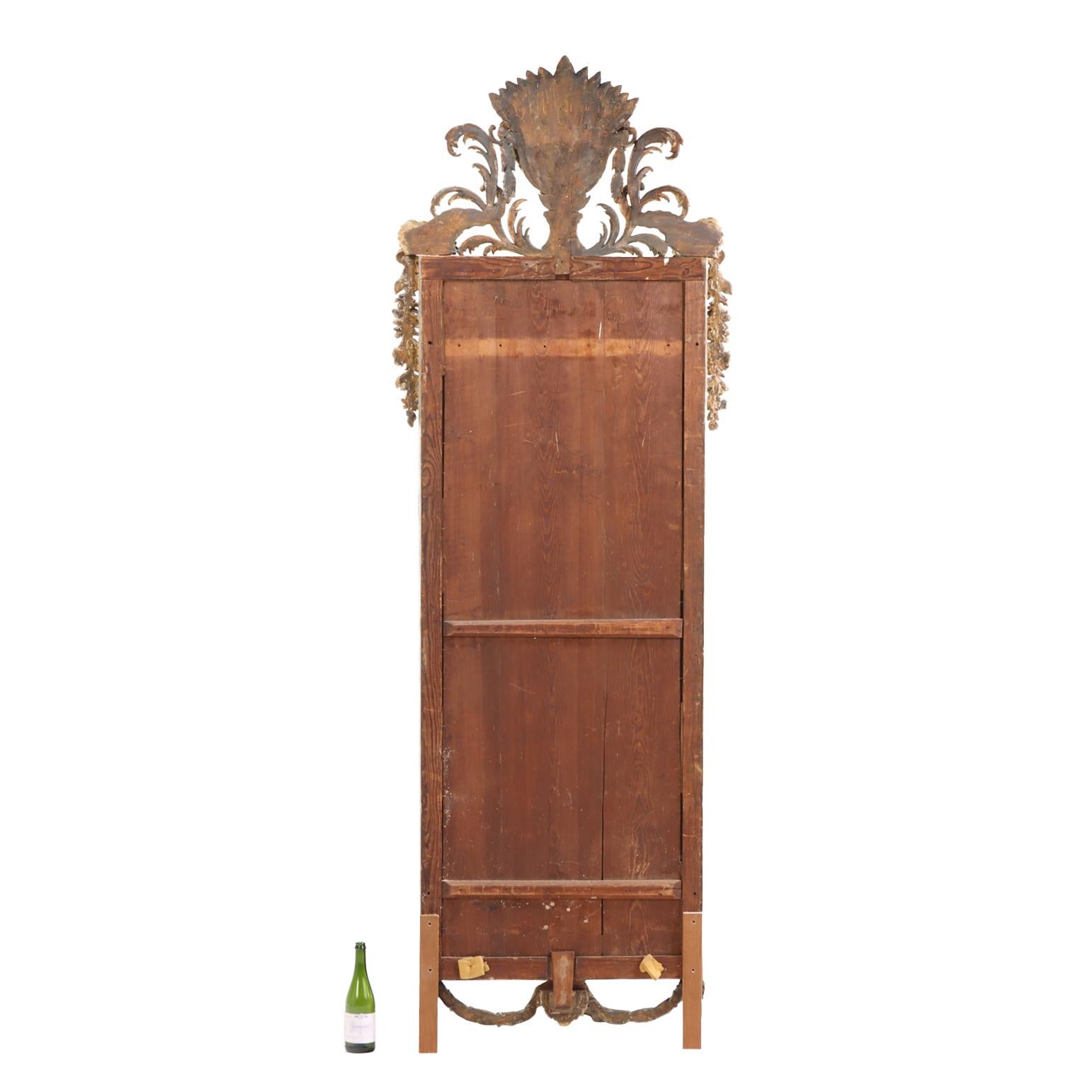 Una scala grandiosa con dettagli in legno dorato riccamente intagliati e sottolineati da accenti argentati. Questo splendido specchio intagliato sarà il fulcro di ogni stanza che adornerà. Coronato da un dettagliato cesto/urna di fiori e affiancato