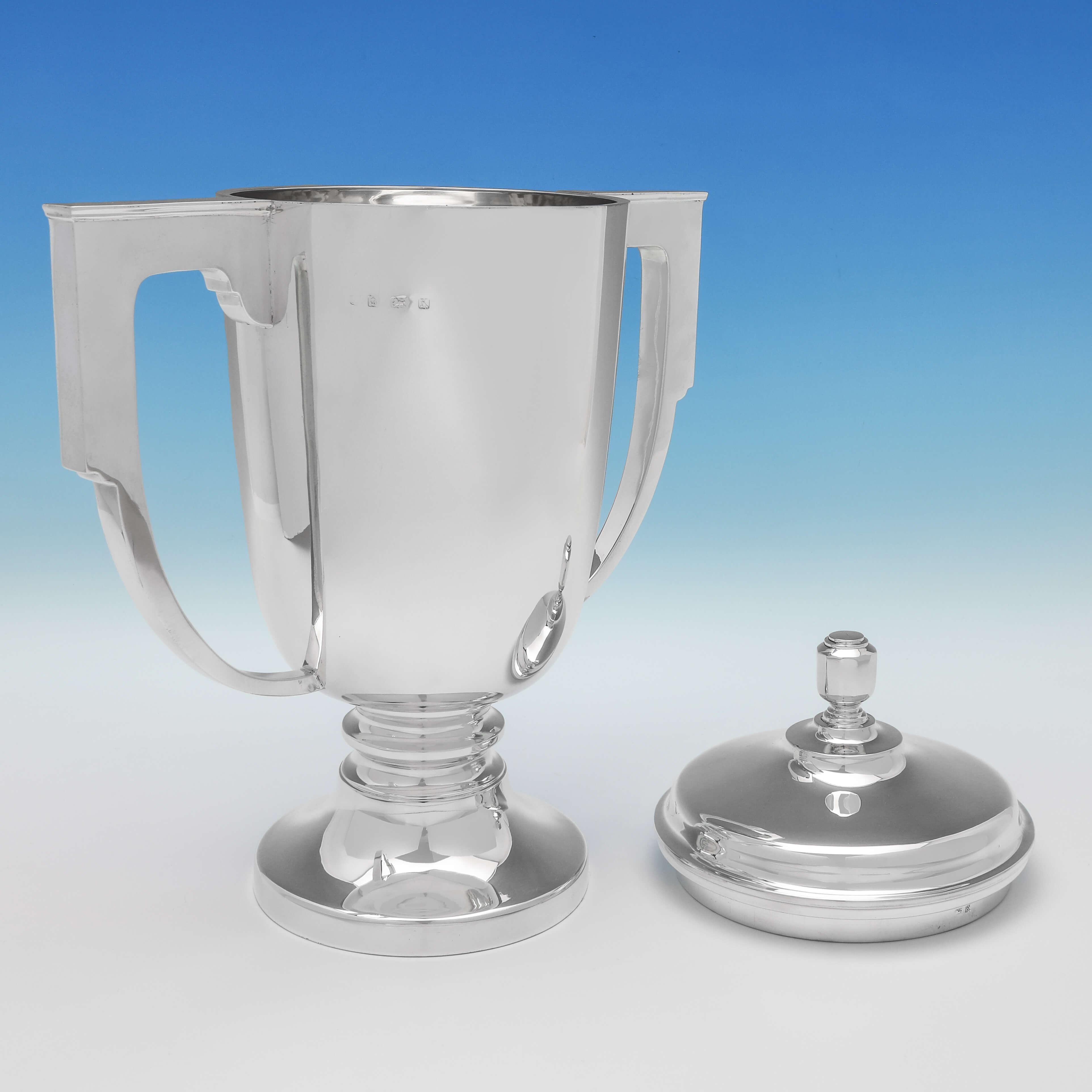 Hallmarked in Birmingham in 1934 by Gibson & Langman, this striking, sterling silver trophy, is in the Art Deco taste, with angular handles, and a plain style. The trophy measures 15.5