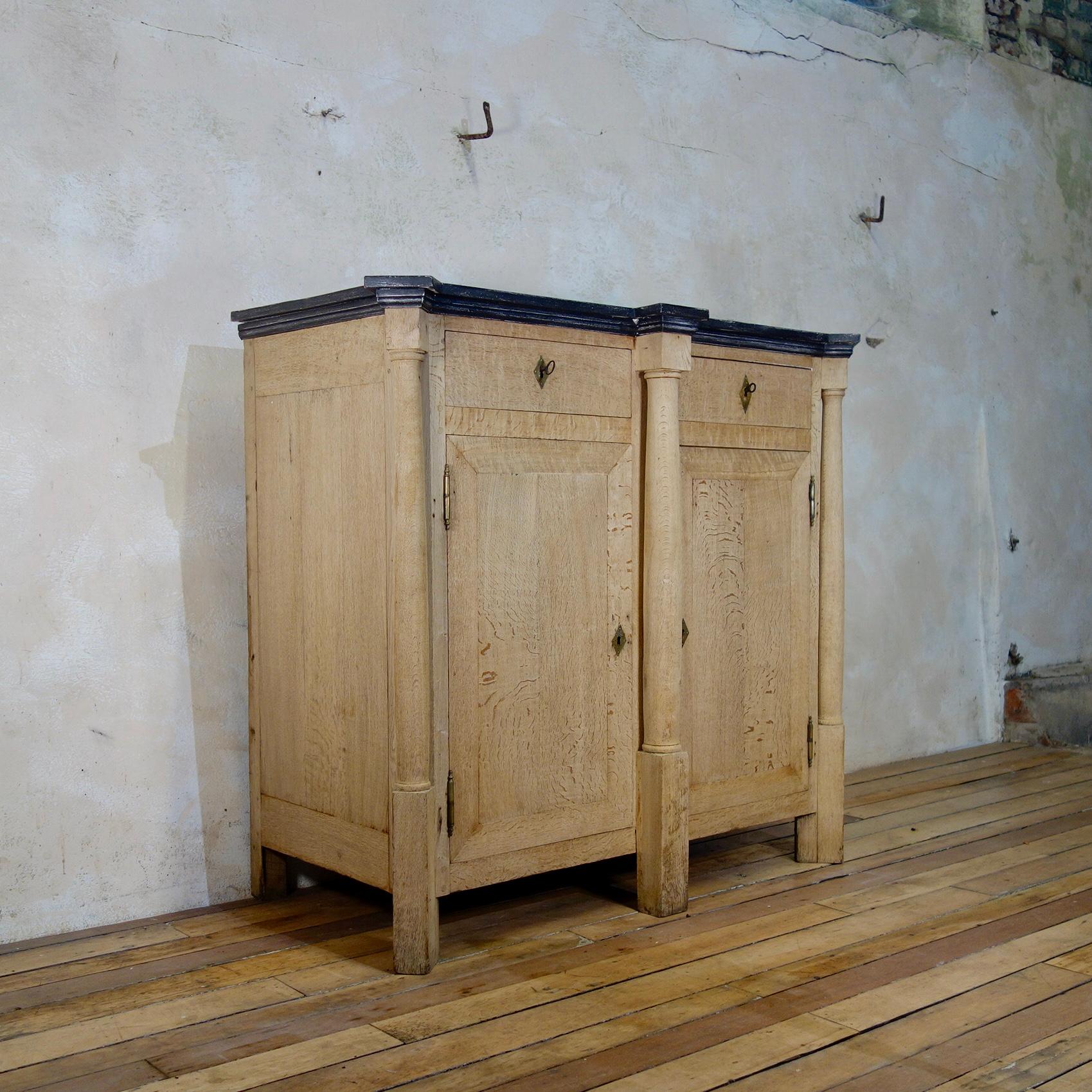 A large tall early 19th century French bleached oak empire side cabinet A charming early 19th-century bleached oak French Empire cabinet. Demonstrating a rectangular-shaped top with overhanging rectangular corners.
Displaying a pair of drawers