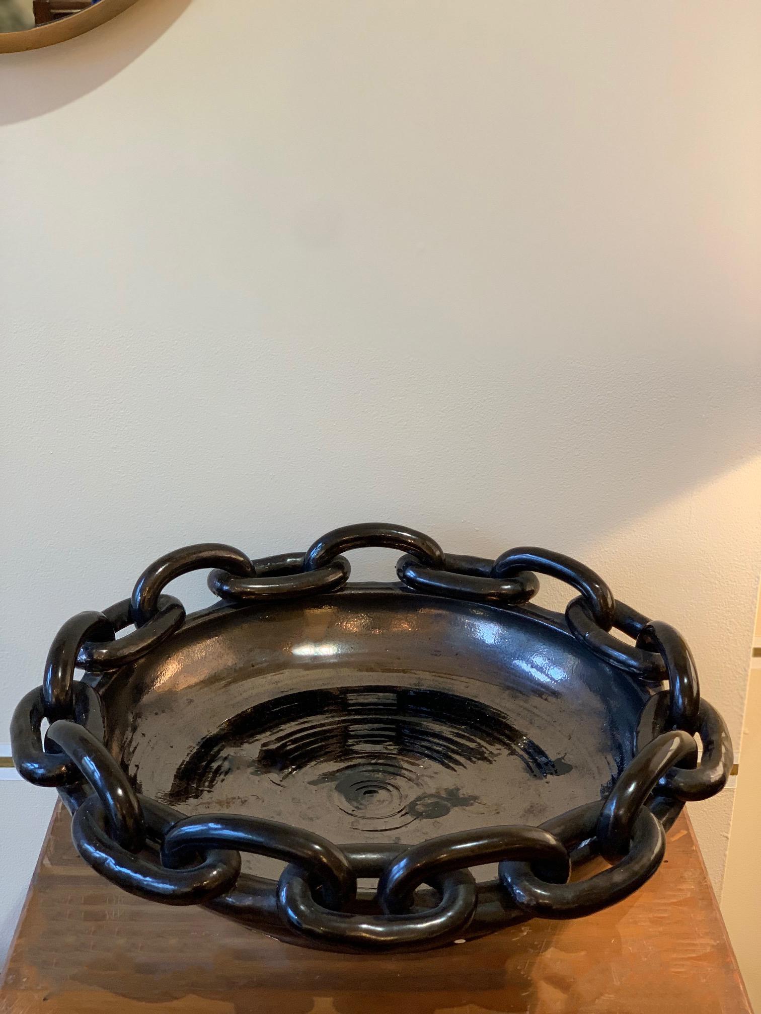 A large black ceramic circular bowl, with a chain links border and a distinctive metallic glaze
by Jerome Massier
Vallauris, France, circa 1950.