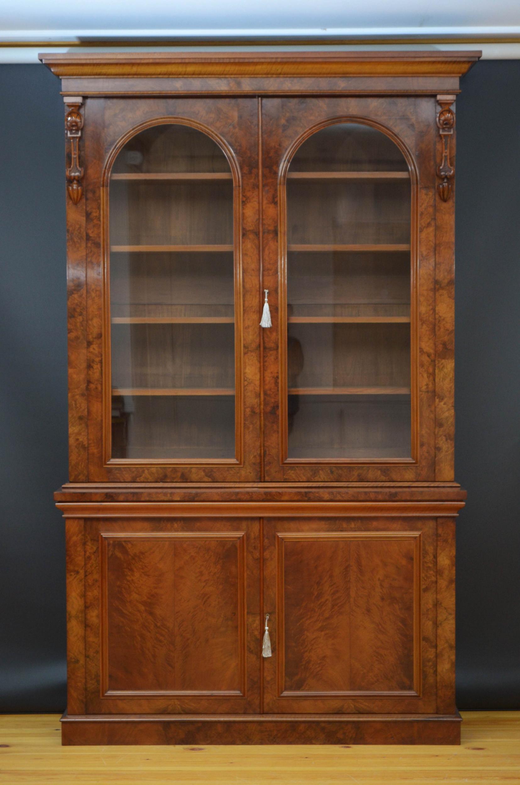 Sn5060 Exceptional Victorian figured walnut bookcase, having outwept cornice above a pair or arched glazed doors enclosing height adjustable shelves and fitted with working lock and a key, all flanked by fine drop carving, projecting base having