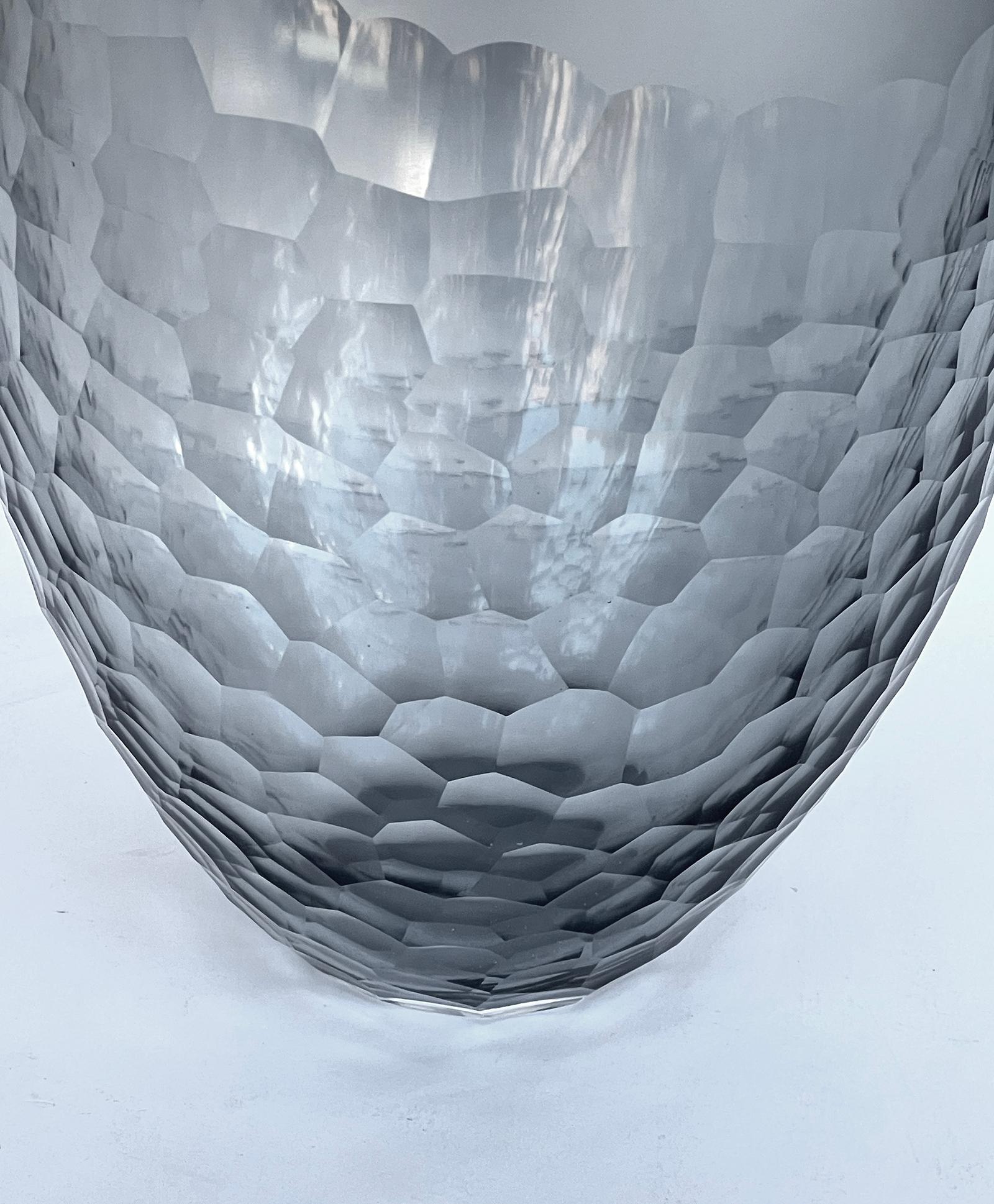 the bullet-form vase in gray glass with oculus opening above a frosted upper section over a carved faceted lower portion tapering to the base; this chiseled glass method is similar to the 'Battuto' style made by Ferro Battato in Murano; 'Rosenthal'