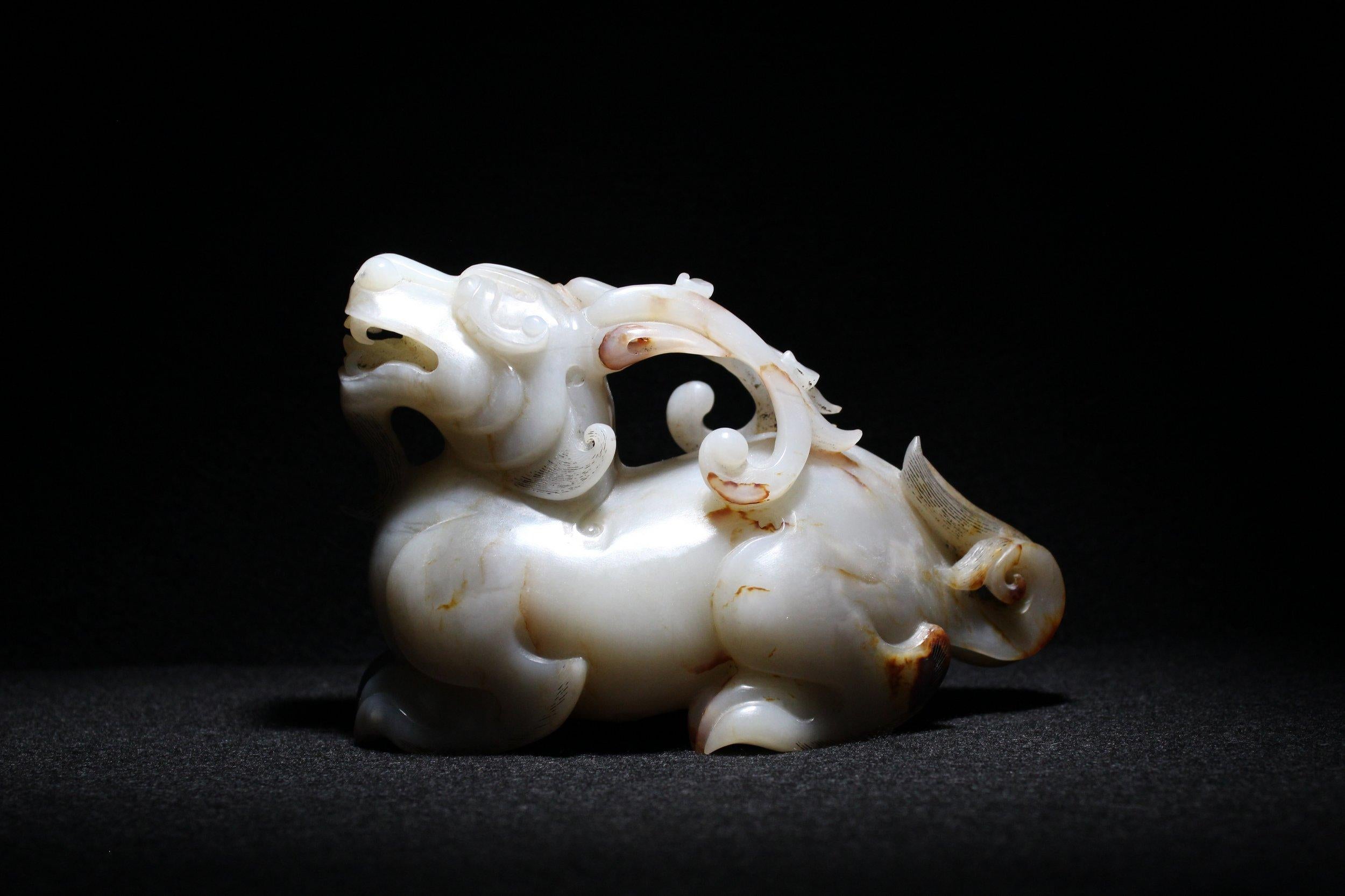 Esta espléndida talla de una bestia mítica yacente es una obra maestra del jade. 

La bestia mítica levanta la cabeza, mirando hacia arriba y hacia delante. 

La bestia está preparada para la acción, sus poderosas y musculosas patas soportan su
