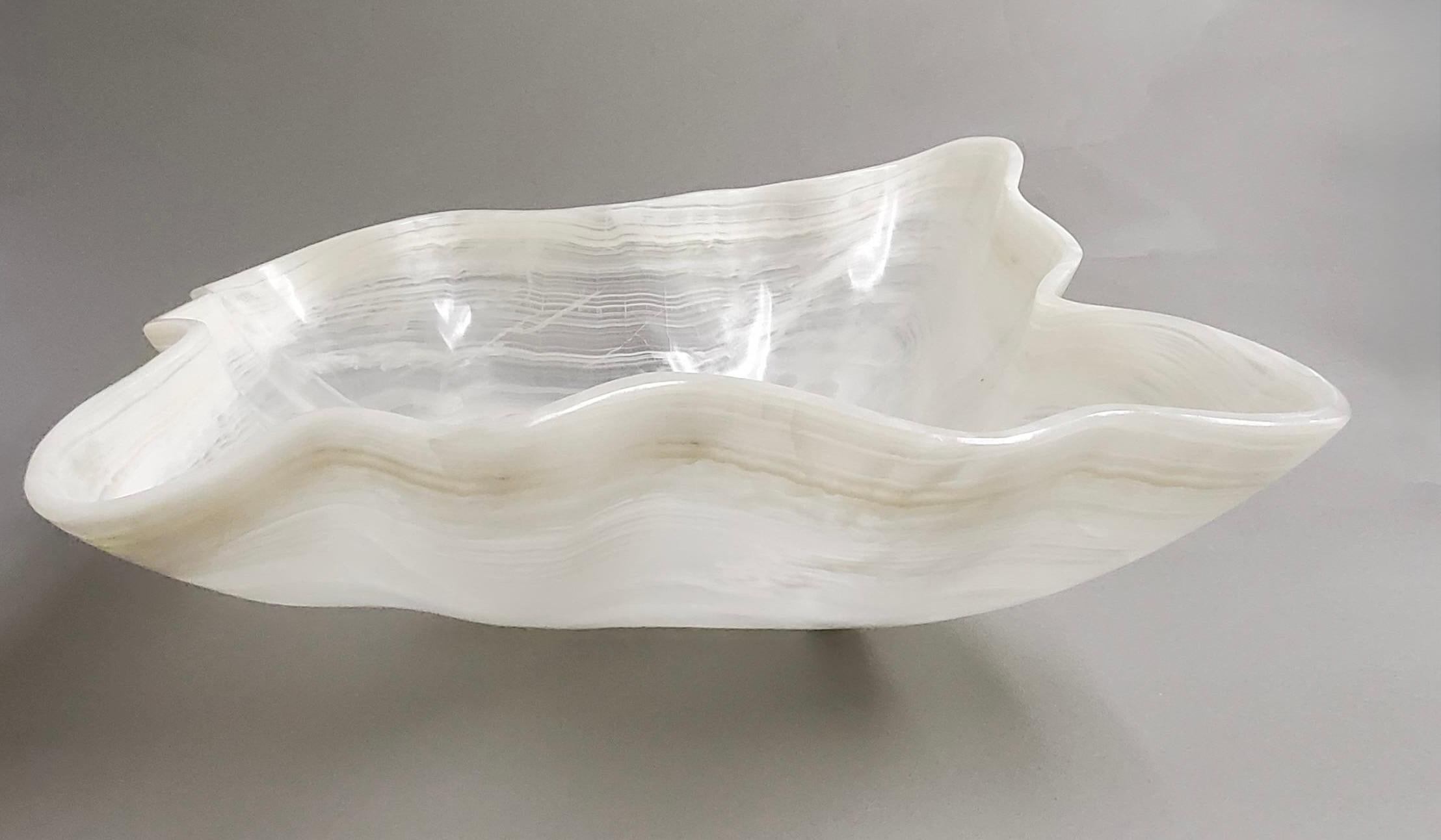 Nous proposons à la vente un grand bol exquis en onyx sculpté à la main, poli pour lui donner un éclat raffiné et une élégance naturelle.  Cette pièce sculpturale présente des bandes d'onyx translucide et semi-opaque dans des tons clairs et blancs,