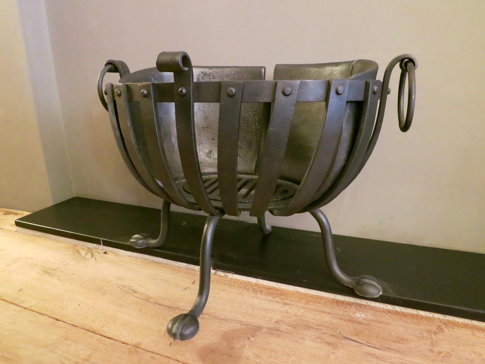 A heavy and substantial oval fire basket, with three paw feet, cast iron plates to retain heat and ring handles. English 
20th century.