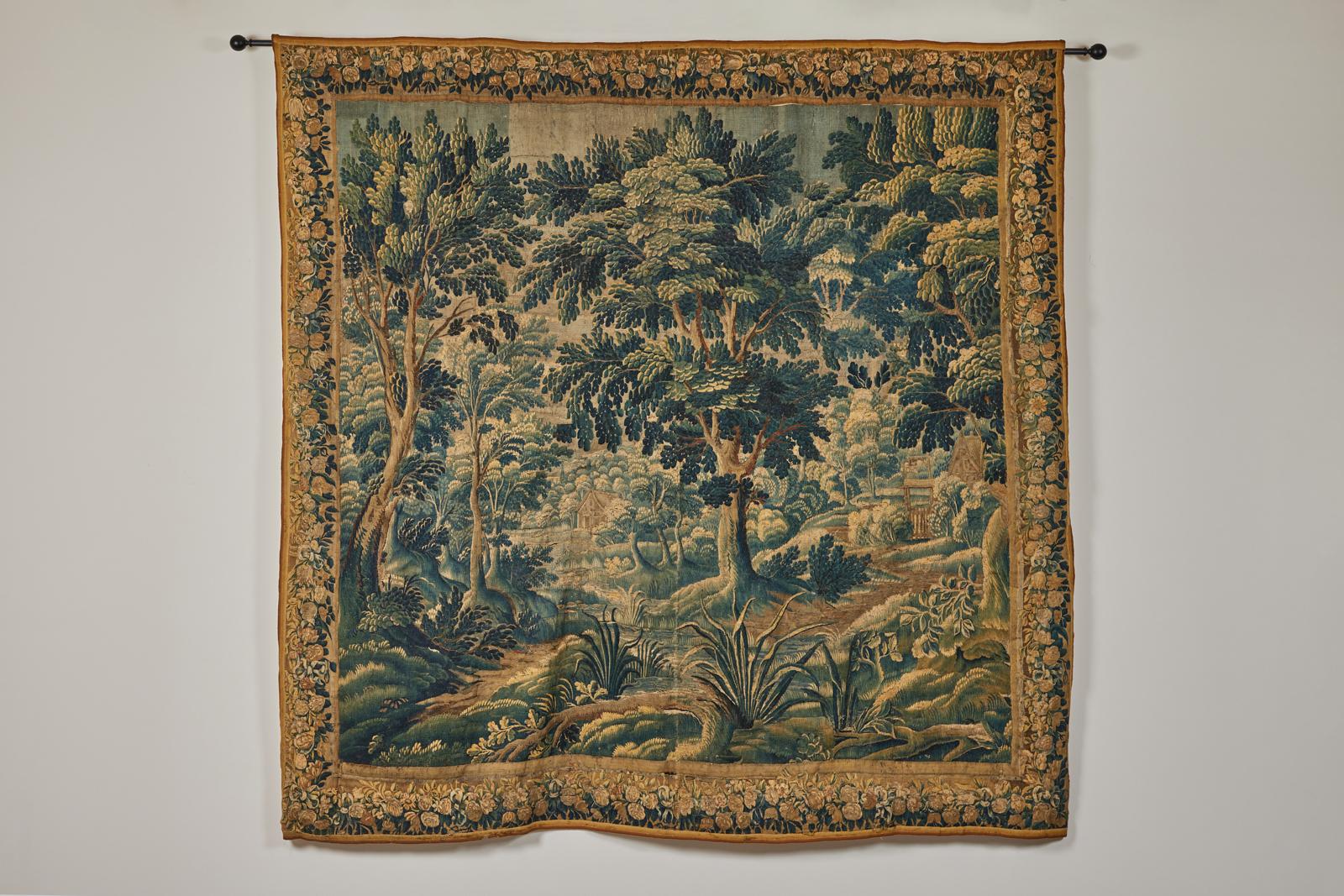 A 17th century Flemish Verdure Tapestry of a lovely landscape scene with a charming cottage next to a forest stream. Finely woven in wools of deep of blues and greens. The tapestry depicts a forest landscape full of rich plant life and verdant