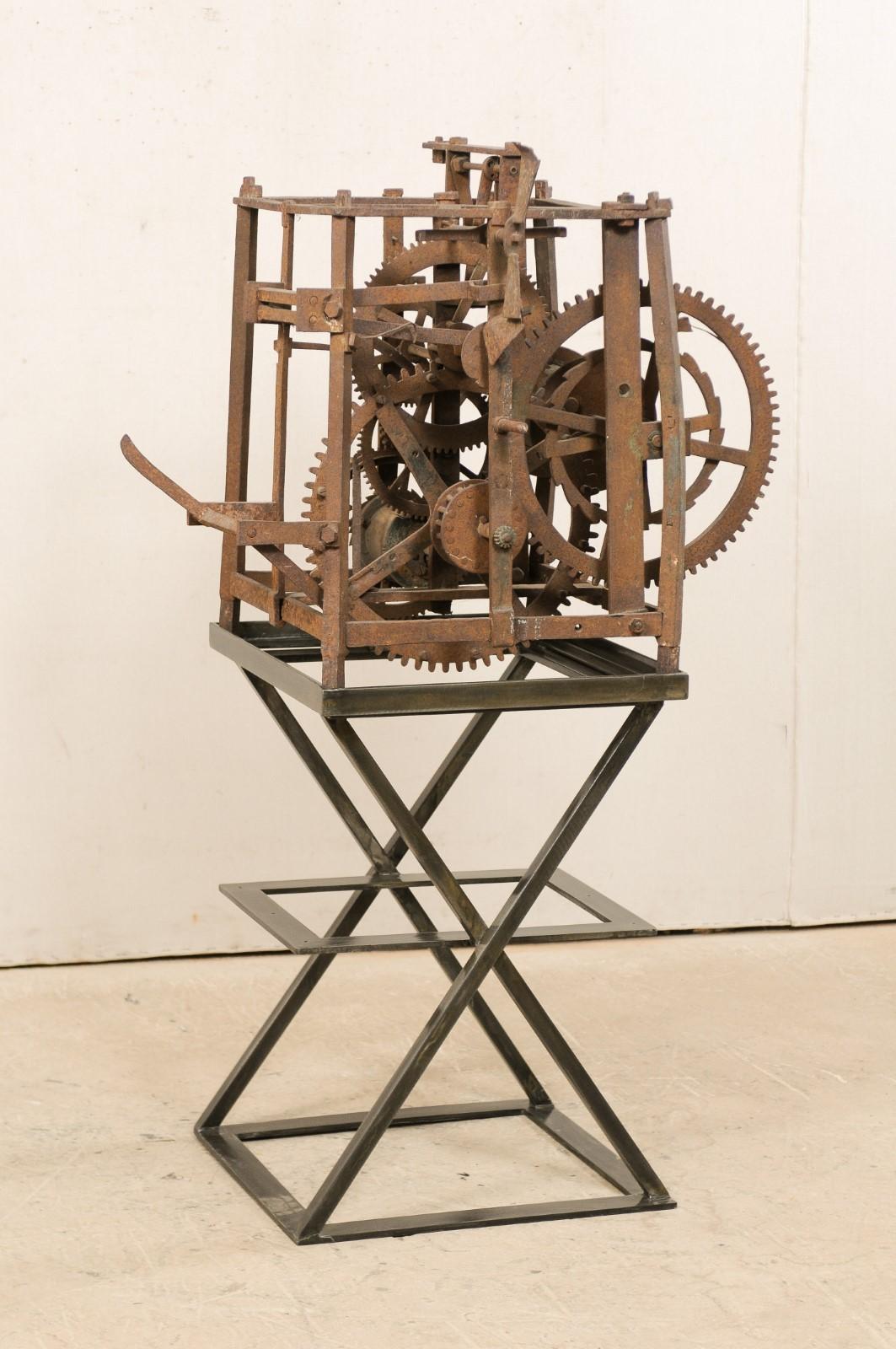 A European clock movement from the late 18th century, displayed on custom iron stand as a modern day art piece. This antique European city clock tower skeleton mechanism is comprised of a series of iron gears and levers, housed together within an