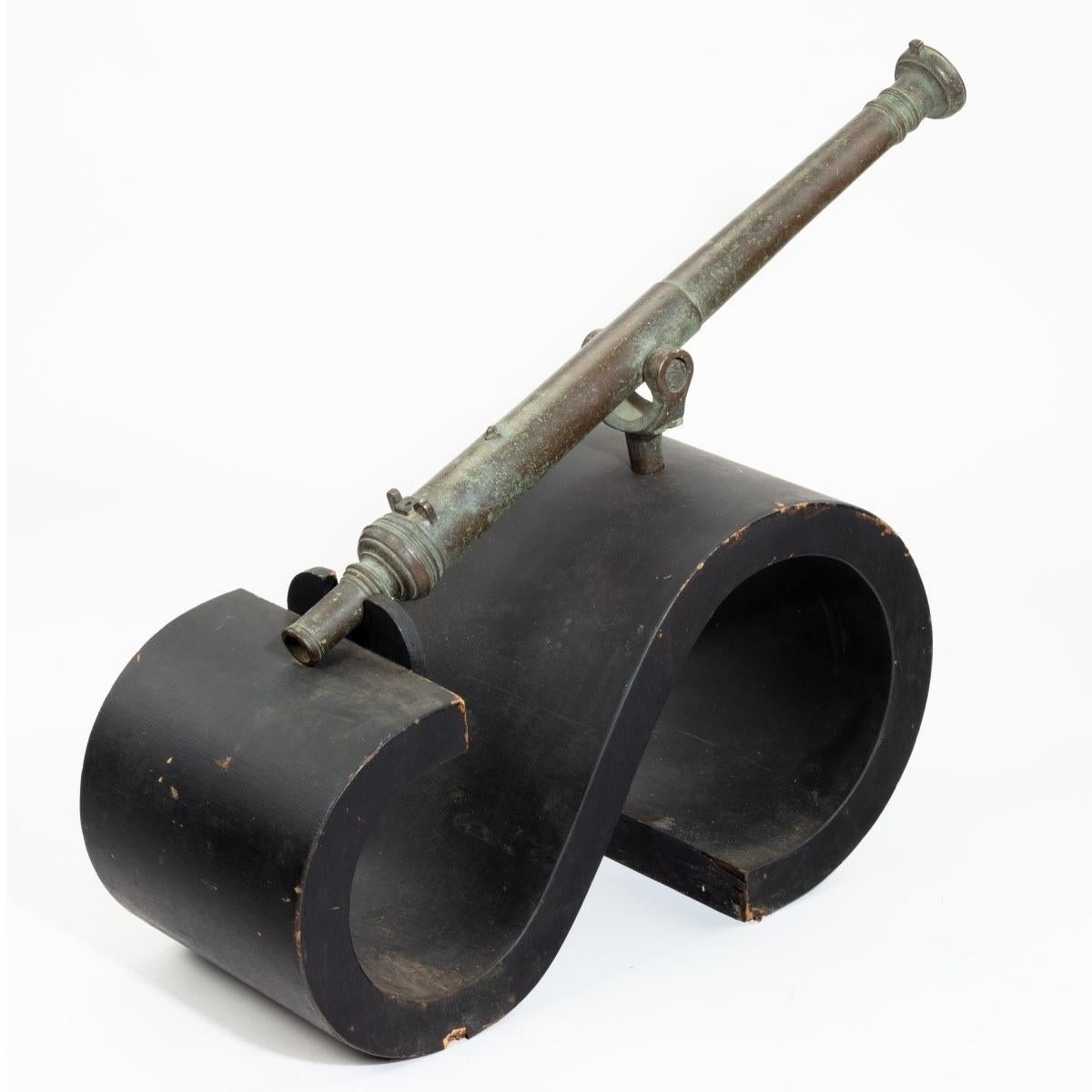 A late 18th century bronze Lantaka cannon, the slightly tapering barrel cast with flanges and set on a hinged pin. With a modern black S-scroll Stand. Dutch, c1790.

Barrel length 33 ½ in????ches.