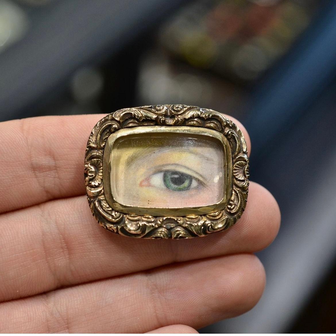 The rectangular brooch centred with a glazed compartment depicting a painted miniature of a lady's eye, frame with rocailles, approx. 3.5 x 2.8 cm, approx. 11.5 g
One curious type of miniature was the “Lover’s Eye”, a subgenre of jewelry that was