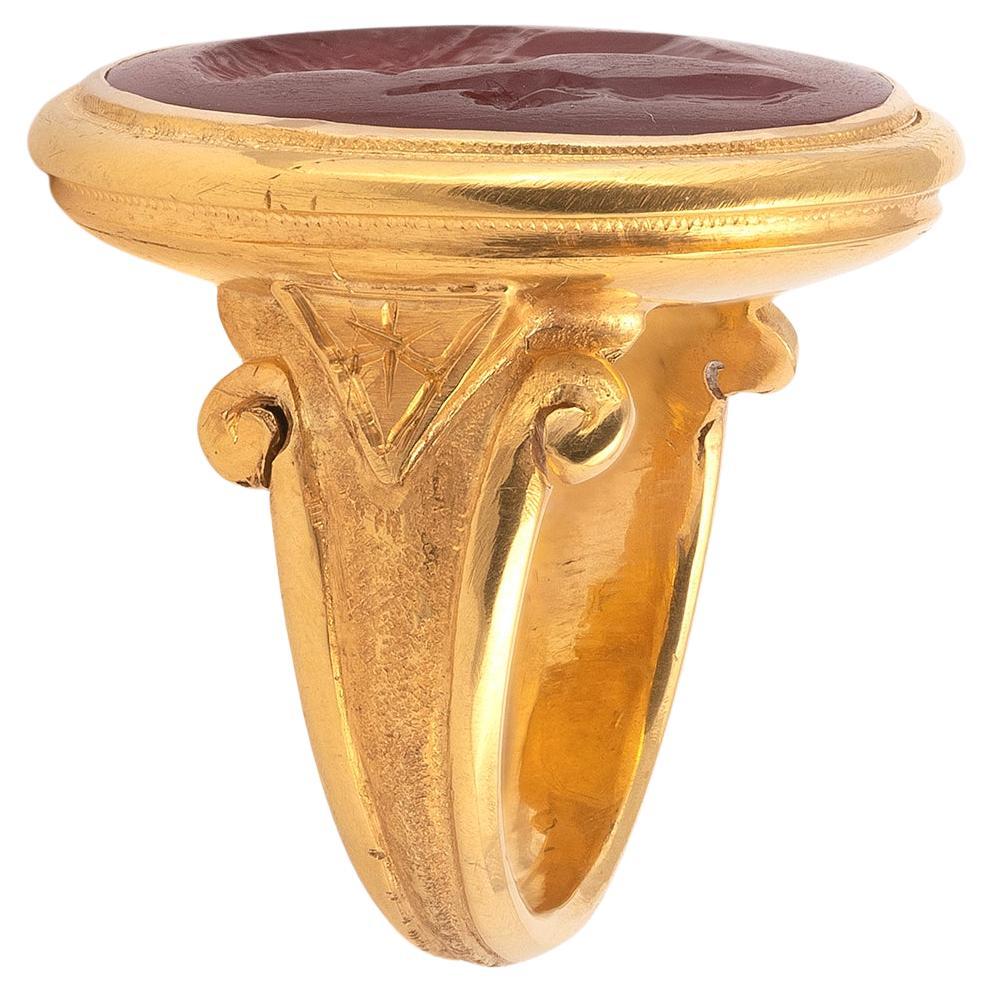 The oval carved carnelian measuring 2.3 x 1.7cm and depicting The silence, rub-over set in gold mount and tapering shoulders, intaglio circa 1790, the mount circa late 20th century, measuring 2.7 x 2.2cm, finger size 7 1/2 , gross weight 22 grams.