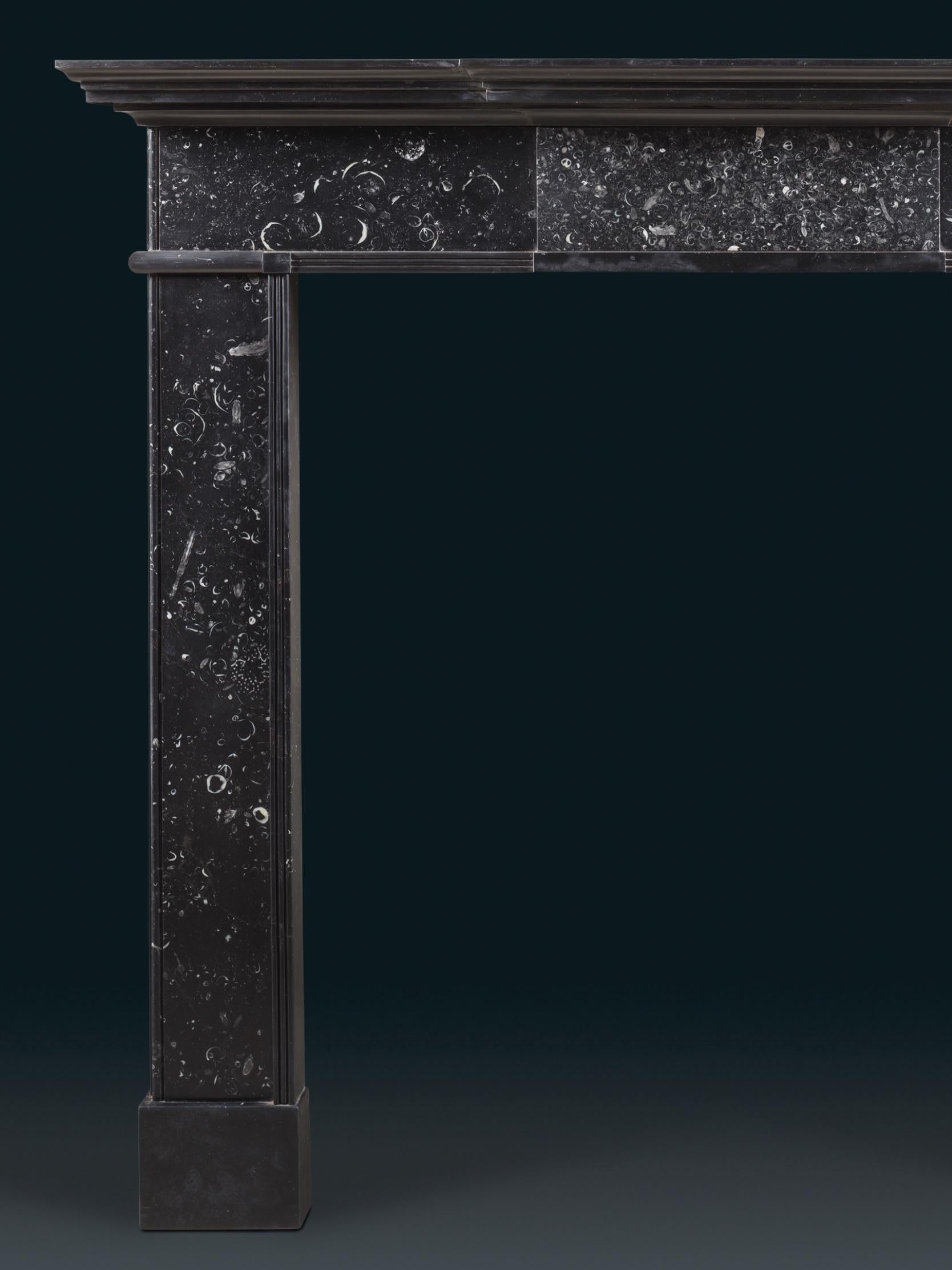 Chimenea georgiana irlandesa de finales del siglo XVIII, de sencilla forma arquitectónica, tallada en una disposición de mármoles irlandeses, Negro y Kilkenny. Una tablilla central lisa, más densamente poblada de fósiles, se asienta bajo una repisa