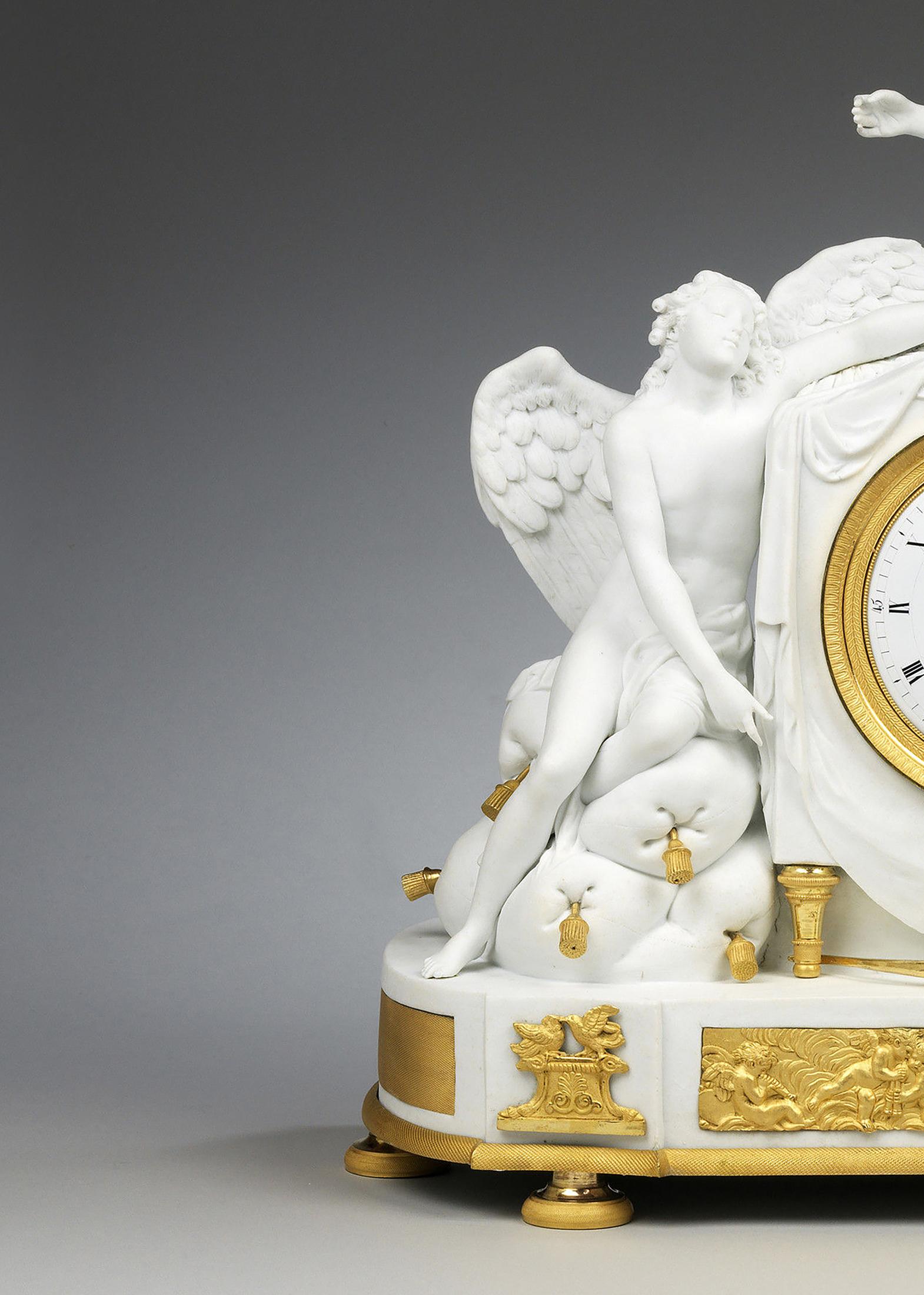 Le cadran de l'horloge émaillé blanc avec chiffres romains, entouré d'un bandeau gravé en bronze doré inséré dans un boîtier en porcelaine biscuit, sur deux pieds tournés en bronze doré. Sur le côté droit, Vénus veille sur son fils Cupidon endormi.