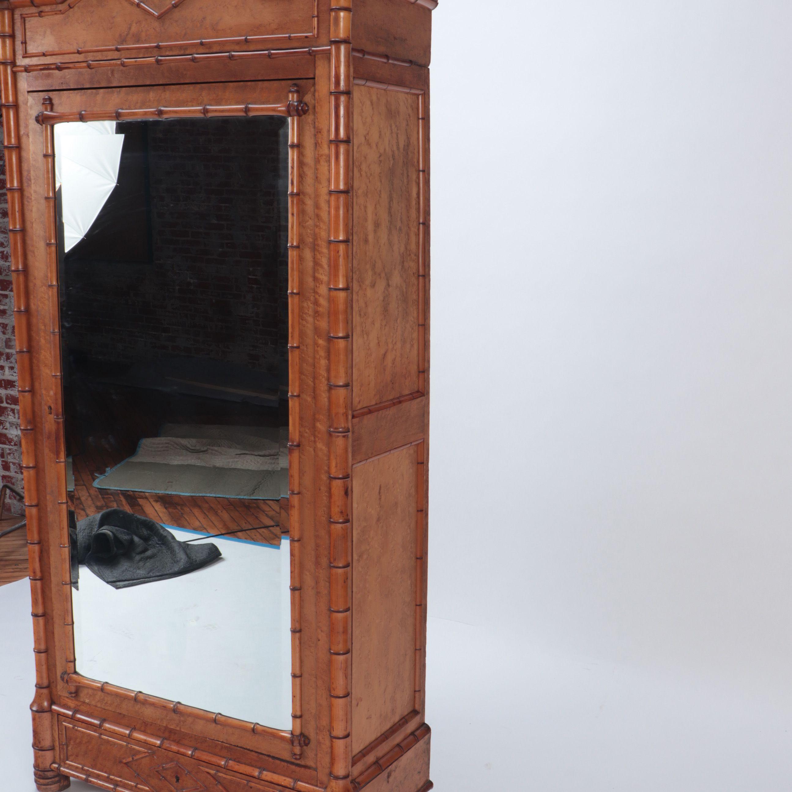 A 19th Century French faux bamboo armoire, or wardrobe, made of maple with faux bamboo details and mirrored door. Turned wood finials and realistic looking bamboo design. Mirror door opens to an interior with four adjustable shelves. One drawer
