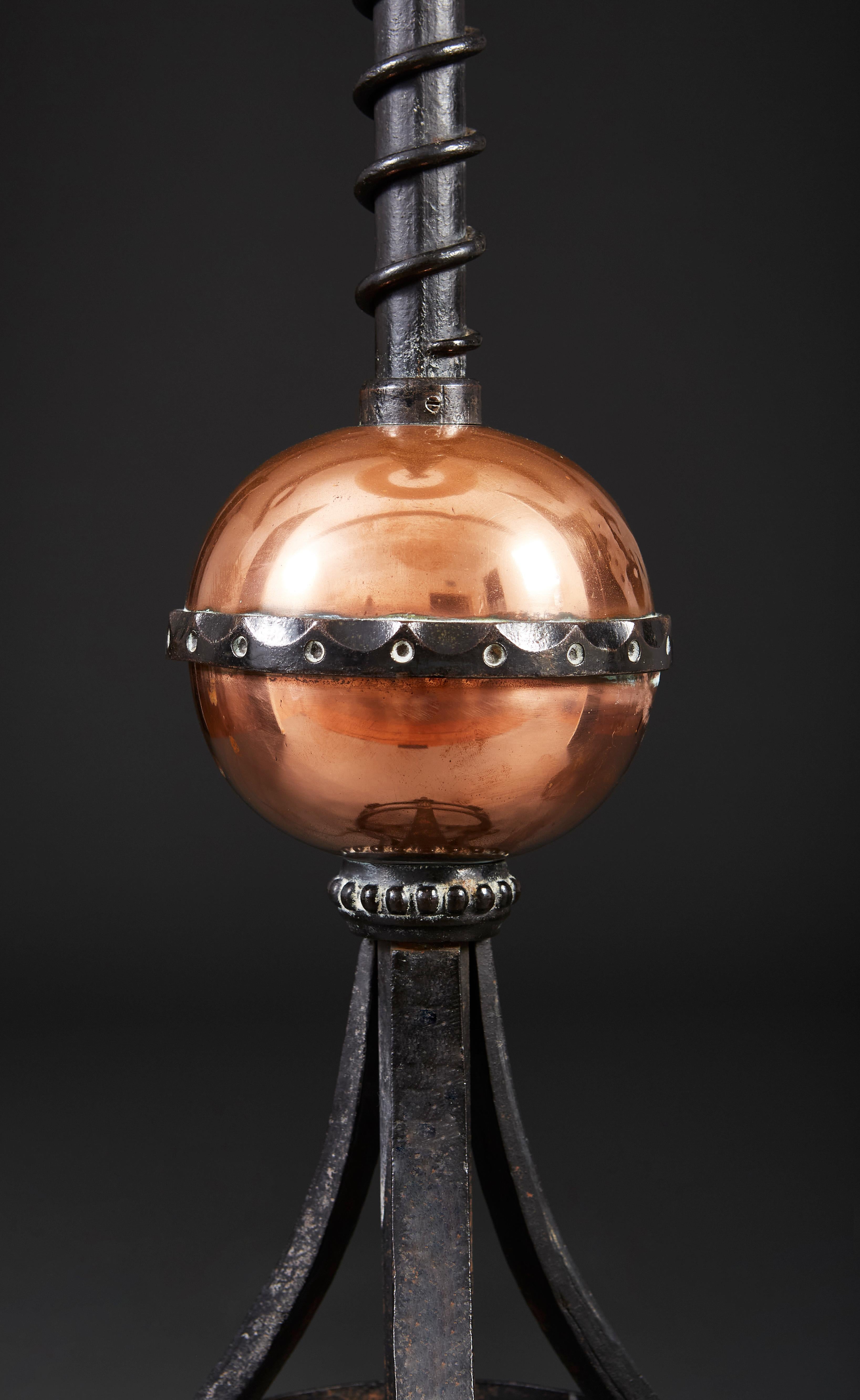 An unusual late nineteenth century wrought iron Arts & Crafts standard lamp with adjustable stem, surmounted by vine leaves to the neck, and central copper globe, supported on a tripod base with scrolling feet.

Please note: lampshade not