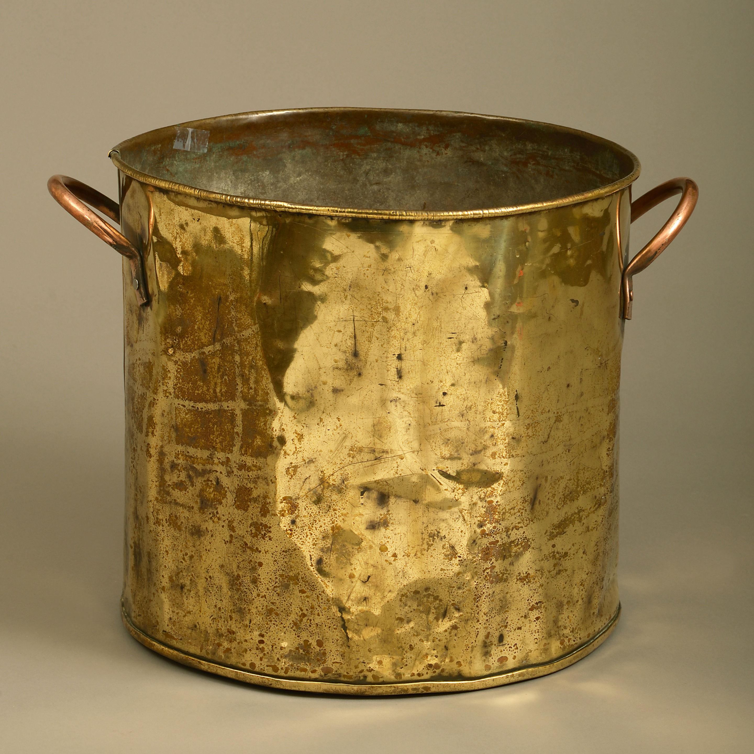 A late 19th century brass log bin, of cylindrical form, having two copper carrying handles.