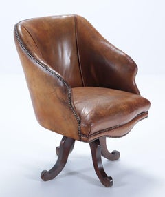 A late 19th Century Continental leather swivel desk chair with nail head trim.