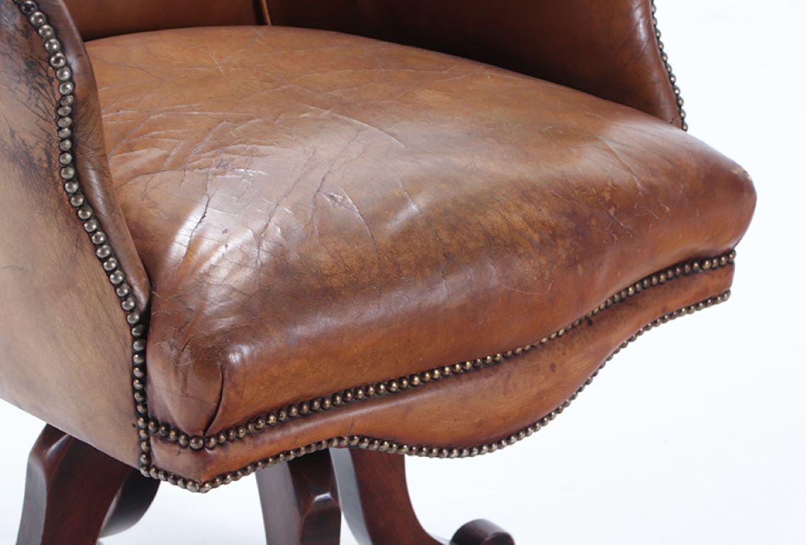 Leather A late 19th Century Continental leather swivel desk chair with nail head trim.