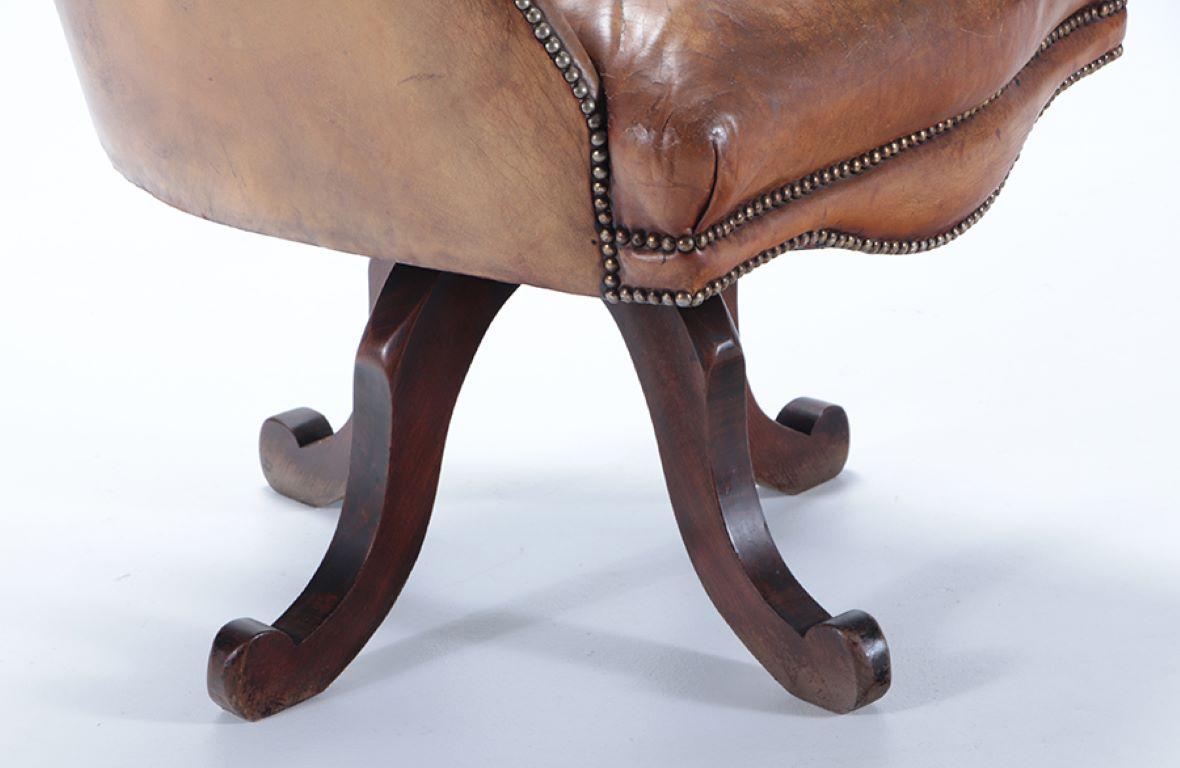 A late 19th Century Continental leather swivel desk chair with nail head trim. 1