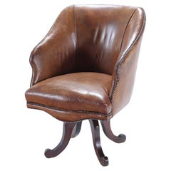 A late 19th Century Continental leather swivel desk chair with nail head trim.