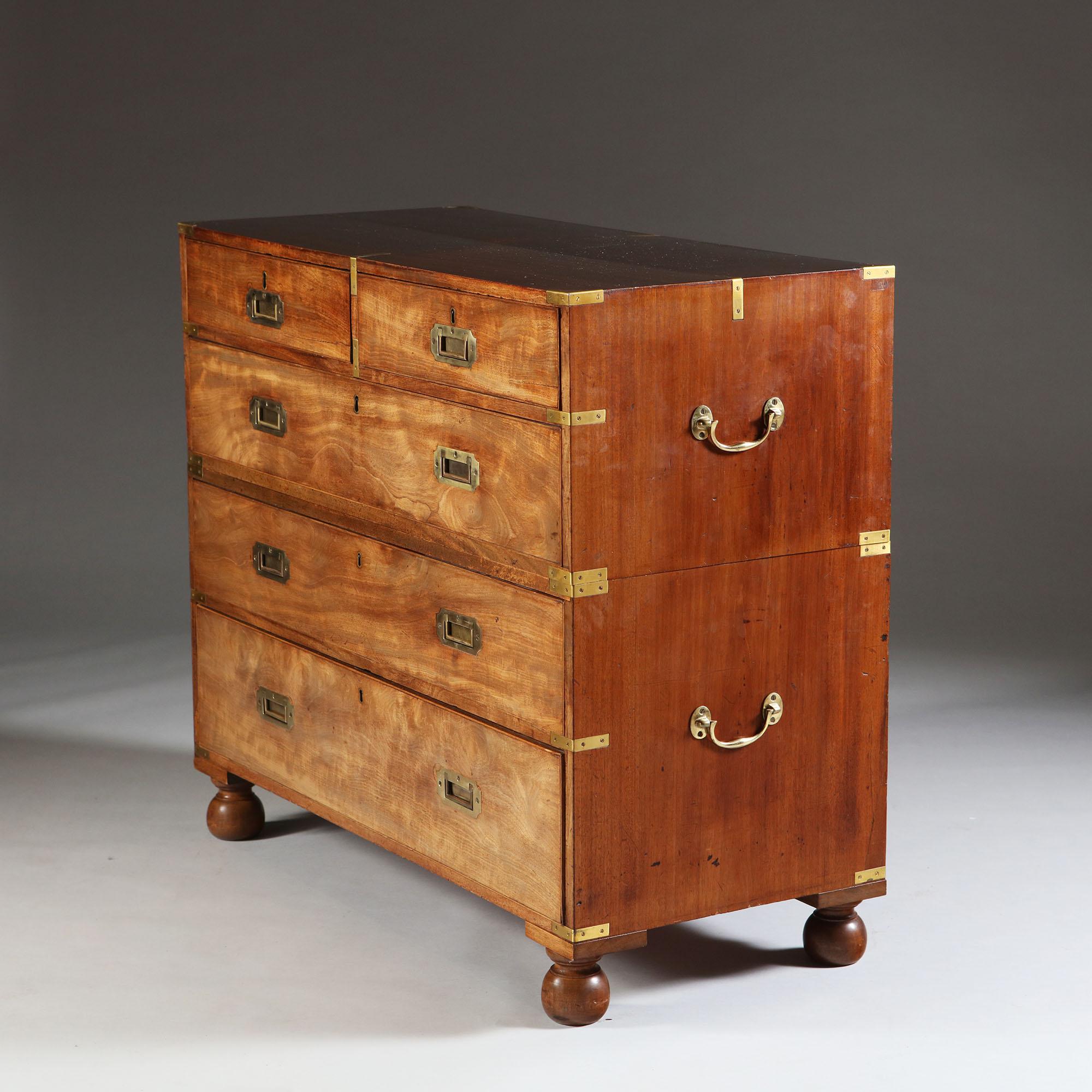 A late 19th century English mahogany campaign chest of drawers in two parts, with brass countersunk handles and brass corners, all supported by four bun feet.