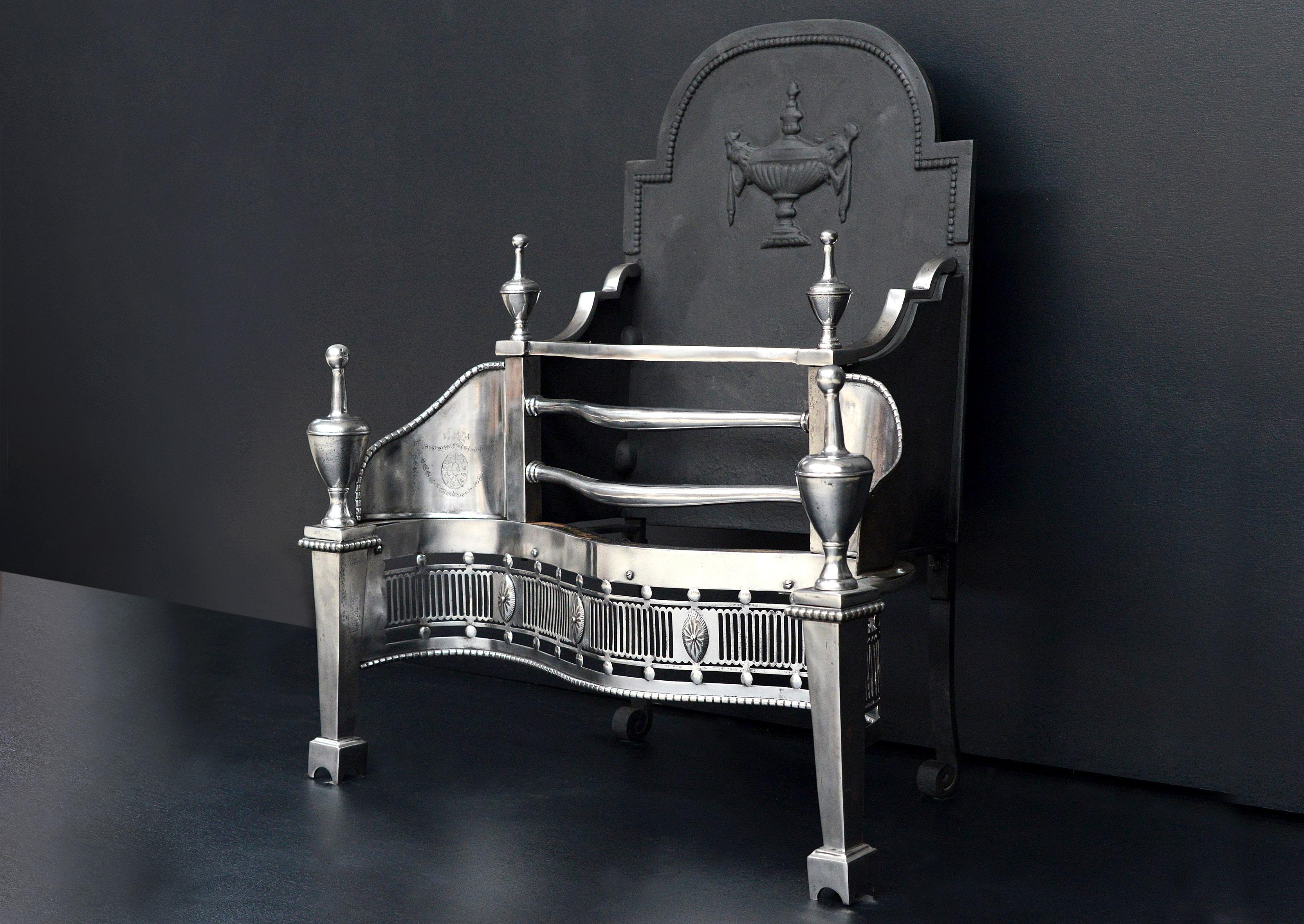 A late 19th century Georgian style steel firegrate. The fluted fret with cut oval paterae, tapering legs with bulbous urn finials, the side panels engraved with swags and paterae. The shaped cast iron backplate with urn detailing.

Width At