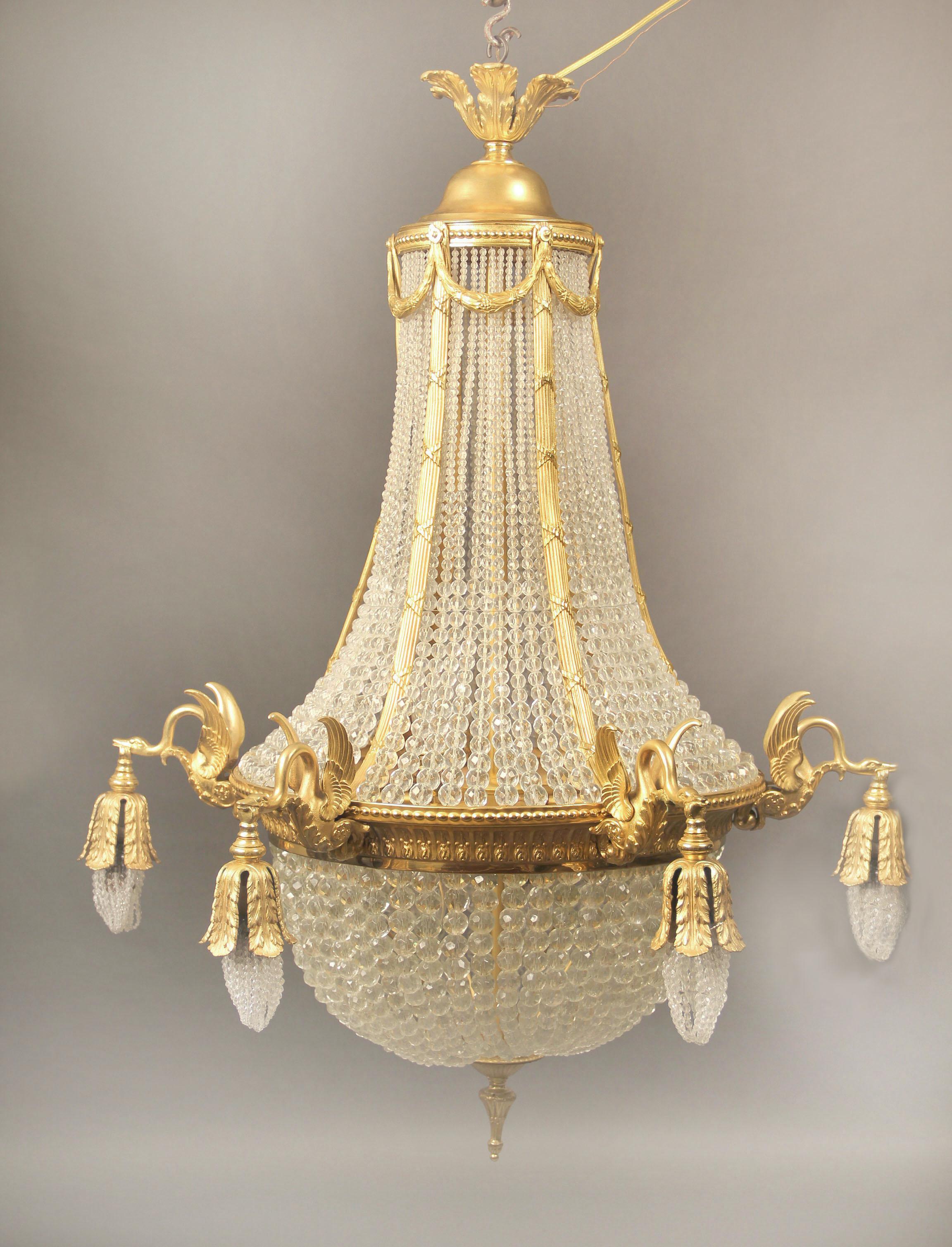 Late 19th/Early 20th Century Gilt Bronze Beaded Basket Twelve Light Chandelier

The upper and lower part of the cage connected by ribbed bronze straps, the straps connected by bronze wreaths, six perimeter lights each held by a swan, six interior