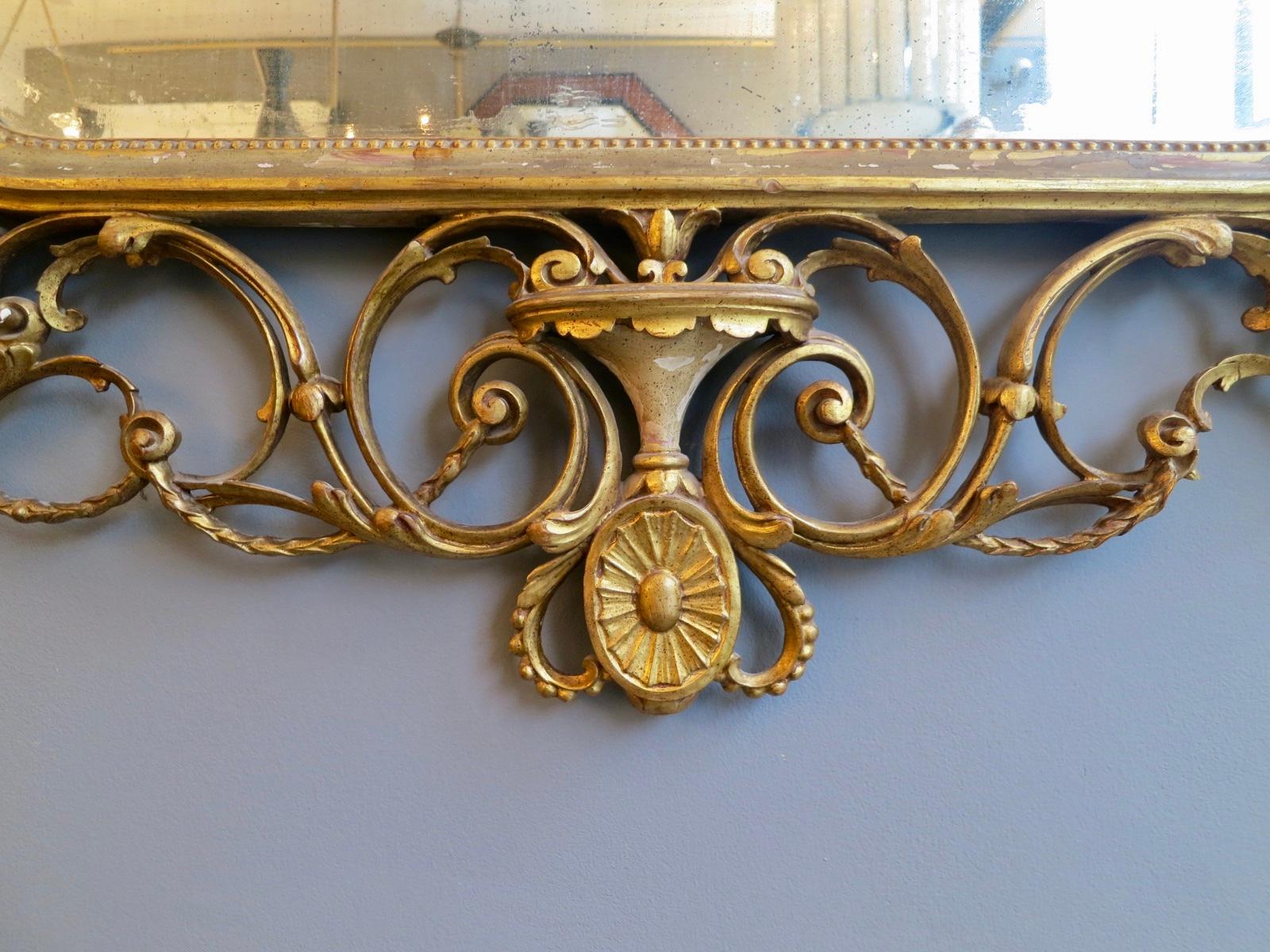 A large neoclassical gilt mirror from the very late 19th century, with very intricate and delicate carving of C-scrolled foliage, rosettes, urns and flowers. The beaded detail throughout conforming on the inner slip, surrounding the original and