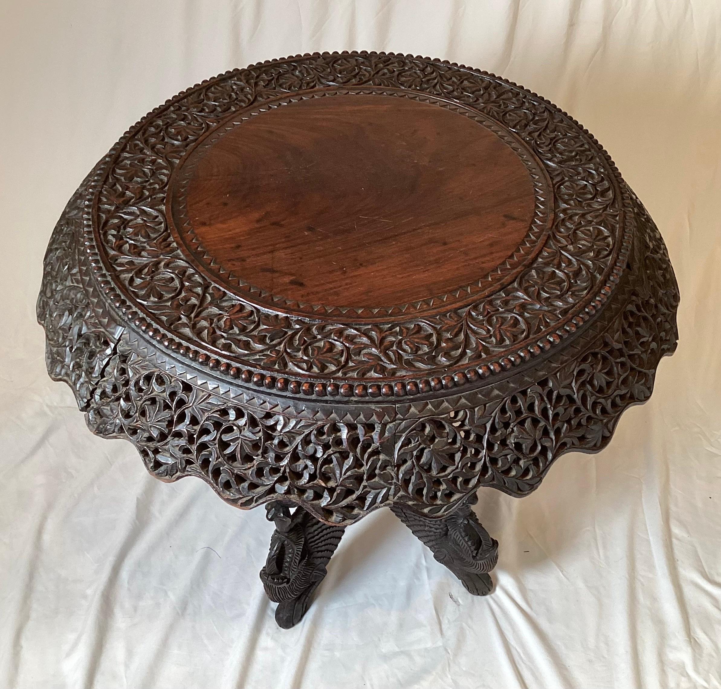Elaborate hand carved round Anglo Indian table. The round top with faired and reticulated apron which revolves on the hand carved serpent motif base. The dark wood with a rich aged patination. Circa 1900, 27.5 in diameter, 27 high.