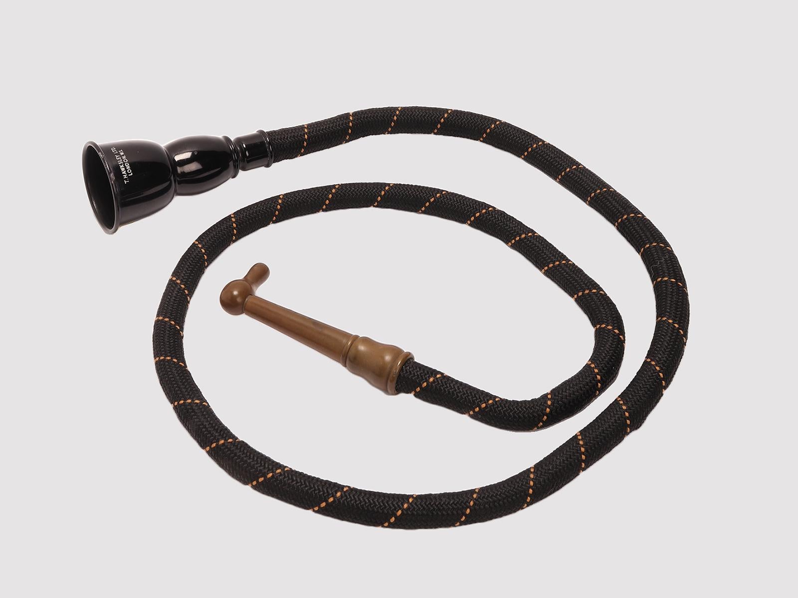 A late 19th-Century medical instrument. A black-enameled brass ear trumpet, of a bell shape, with tapering extension piece with vulcanite end. A cord-bound conversation tube. London - UK circa 1890.