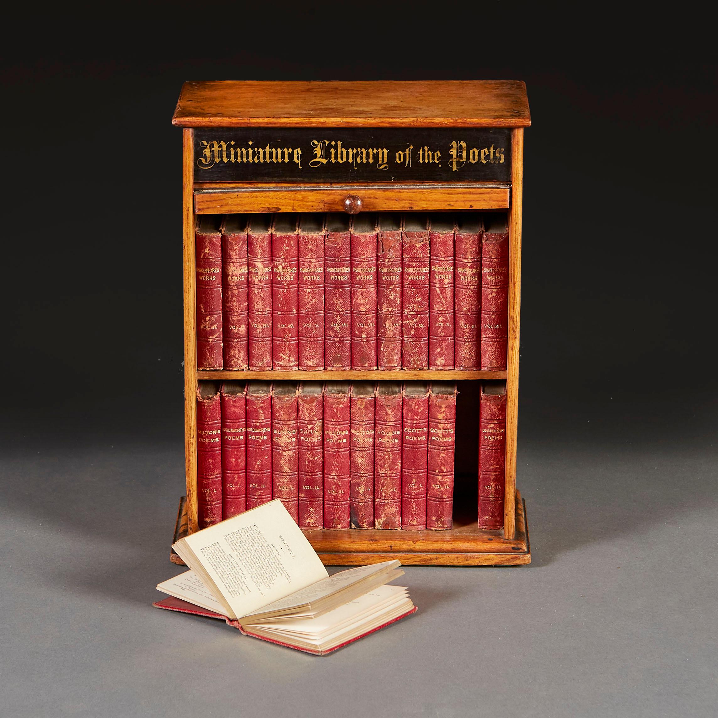 A late nineteenth century oak miniature bookcase, with a library of red leather bound books including the great poets of Britain such as Shakespeare, Burns, Scott, Wordsworth.