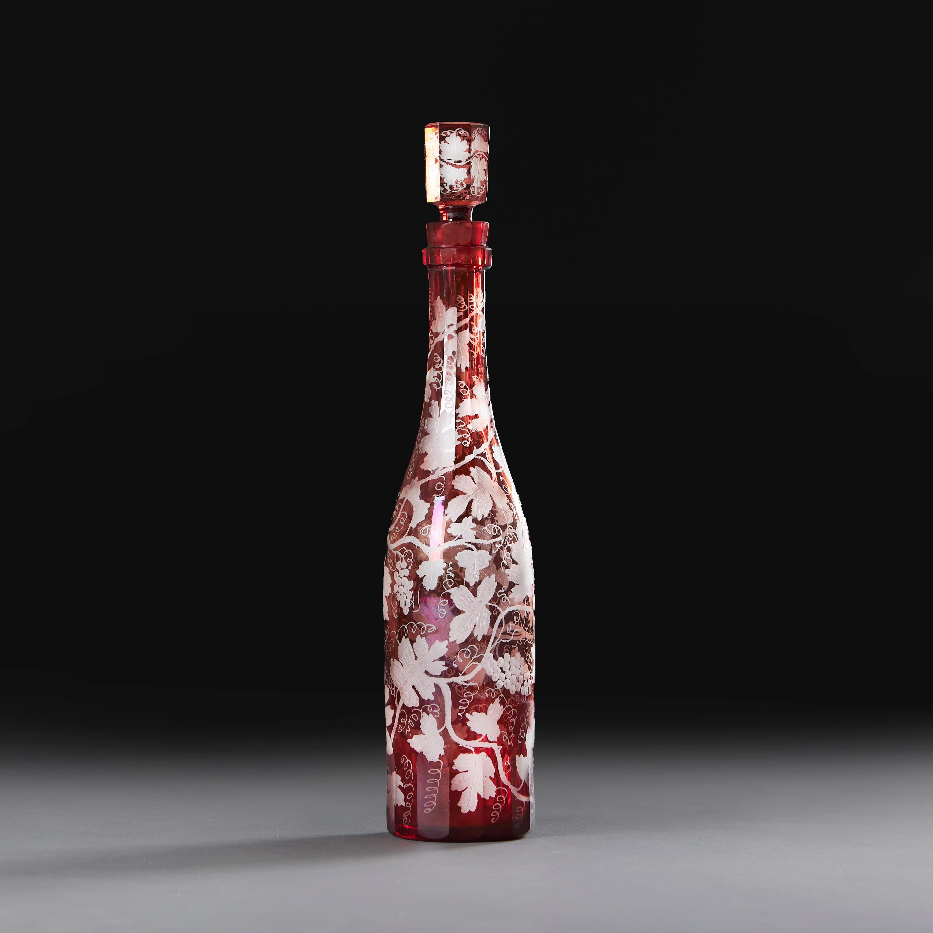 Une belle carafe en verre rouge taillé de la fin du 19e siècle, de forme facettée, gravée de vignes et de raisins sur toute sa surface et conservant le bouchon facetté et gravé d'origine.