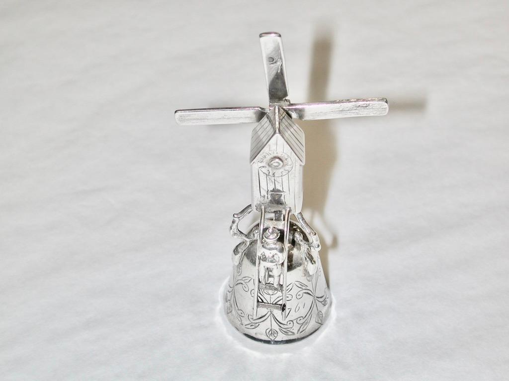 A late 19th century Dutch miniature windmill wager cup, circa 1890, bell shaped flat chased cup, with cast 
roof mill with novelty mechanical sails and attached ladder with climbing figure, Dutch hallmarks
Heavy gauge silver with owners initials and