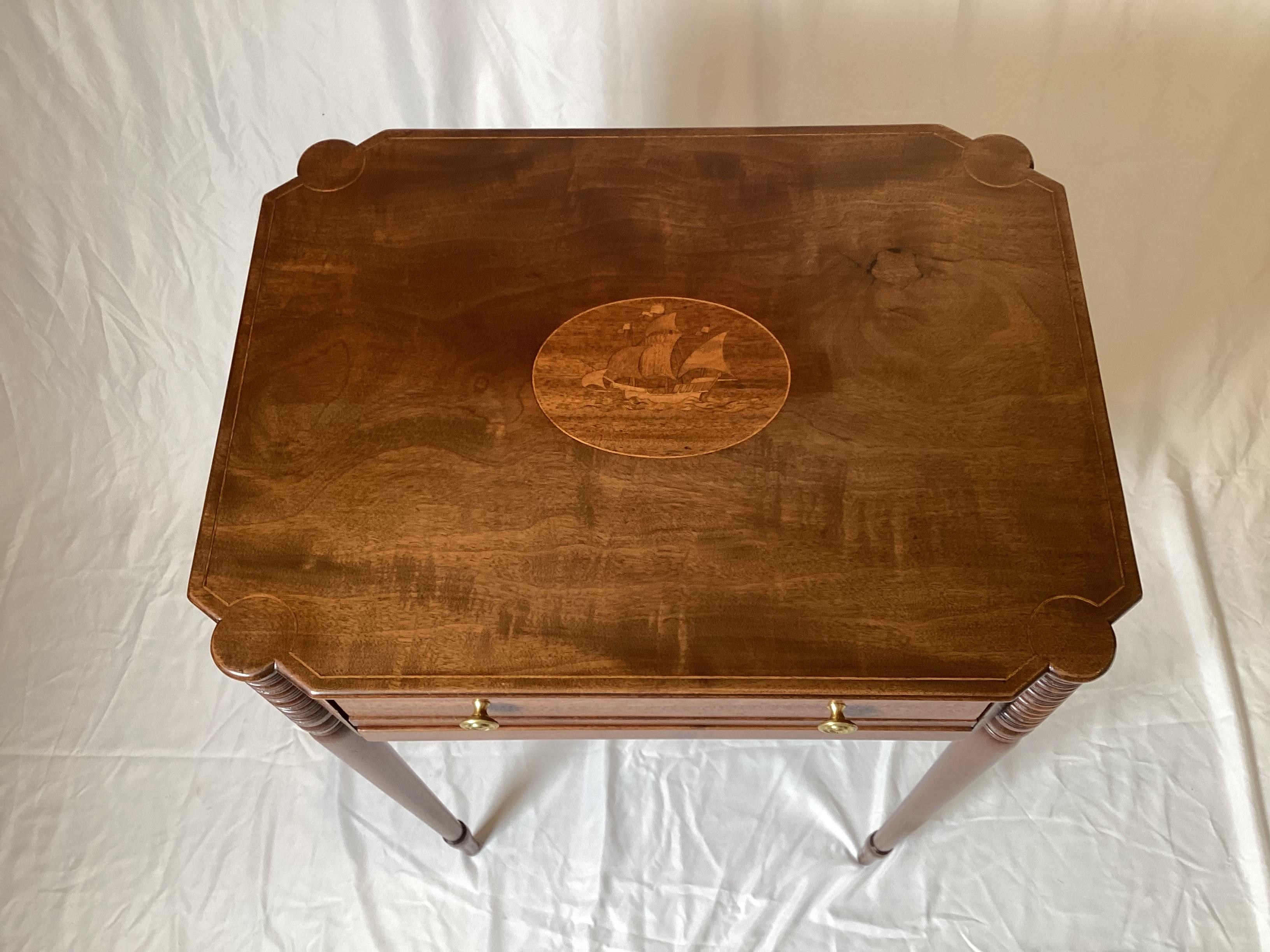 Table de couture et de travail majestueuse en noyer incrusté avec pieds tournés, tiroir unique et rangement coulissant recouvert de tissu pour les nécessités de la couture.  Le plateau est orné d'une rare incrustation en forme de navire.  29 pouces