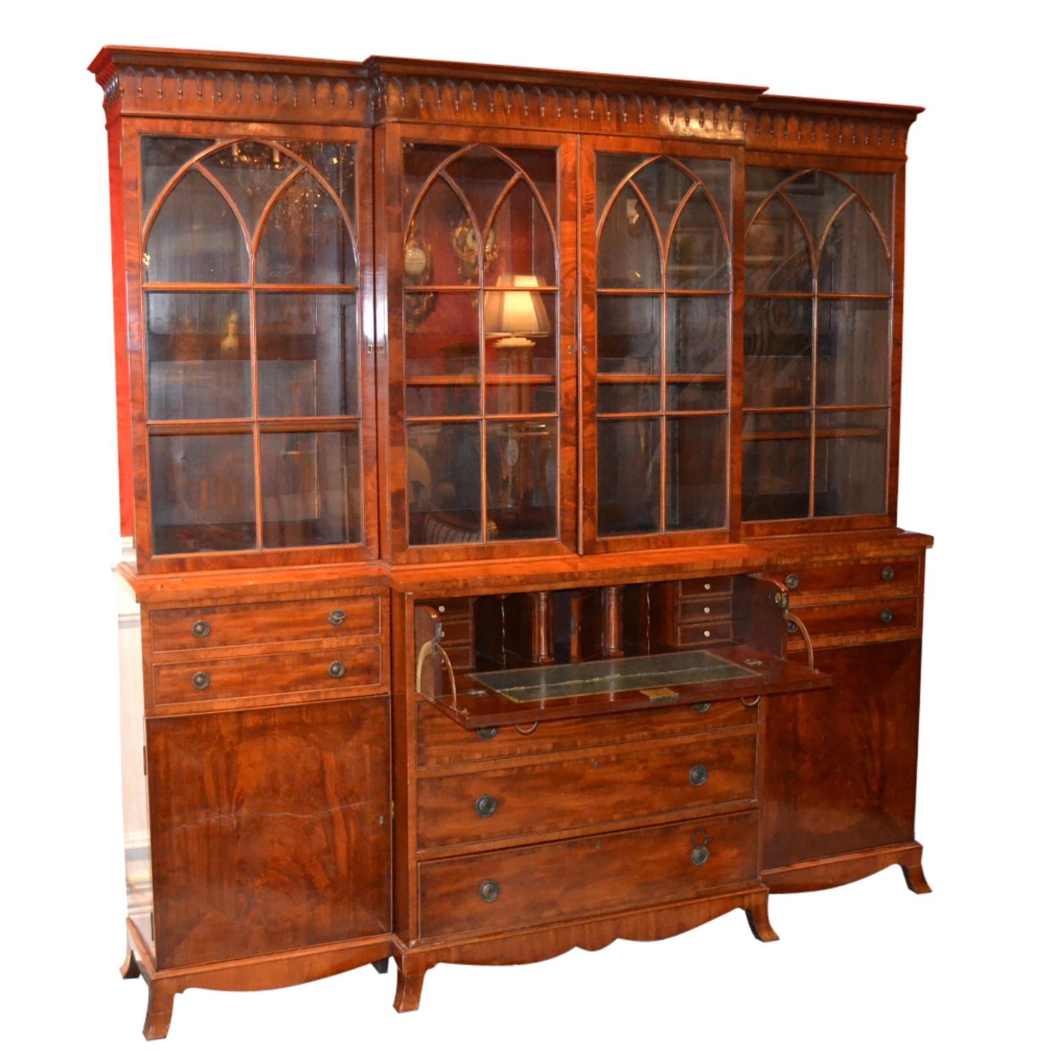 A late George IV breakfront bookcase/china cabinet and pull out desk in beautifully figured mahogany with some Gothic tracery elements along the top. The cabinet is in three sections, the outside two having two top locked drawers, (accessed from