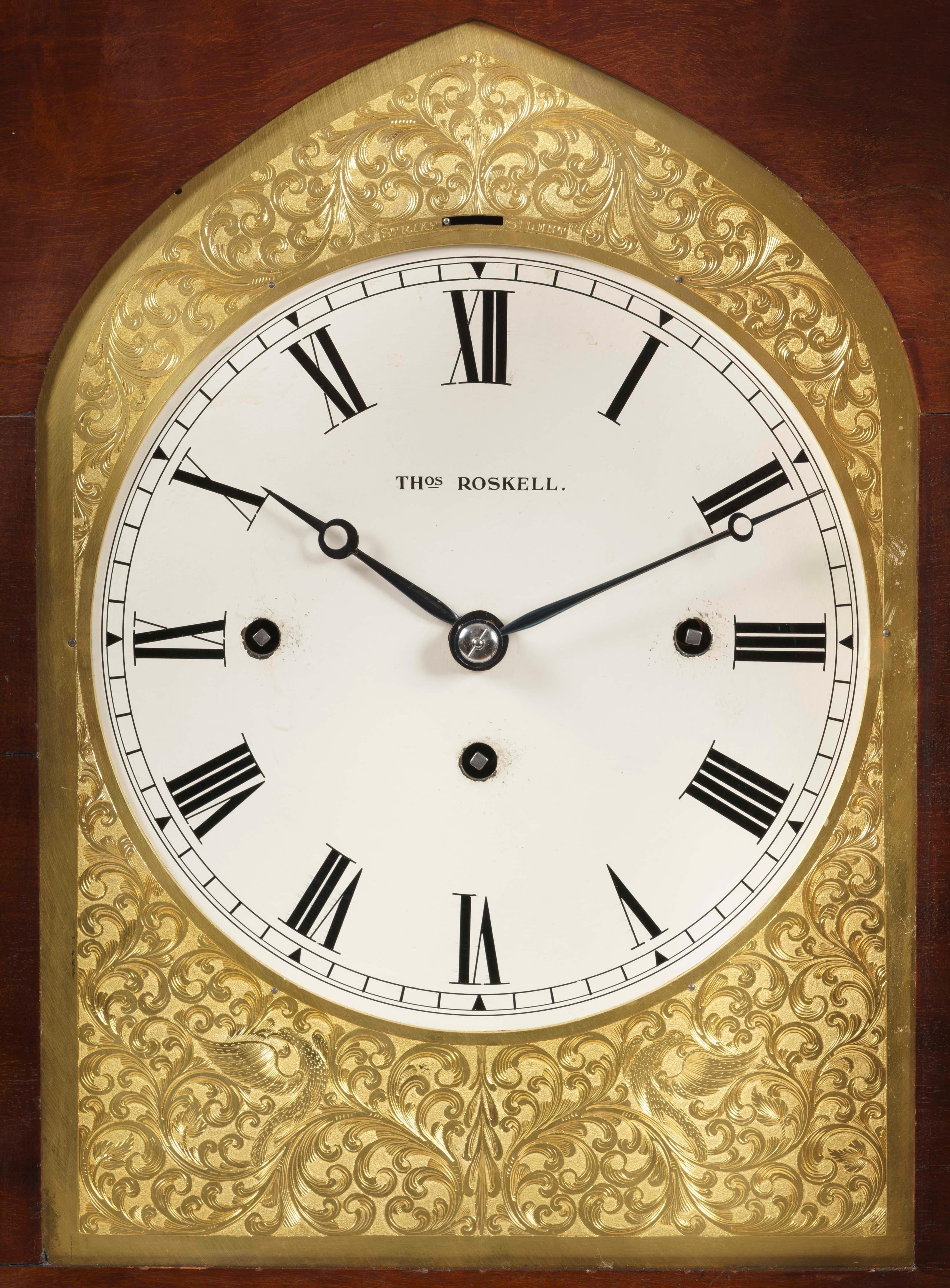 A Late Georgian Musical Table Clock
By Thomas Roskell

The well patinated carved mahogany case having a fluted and foliate carved pagoda top surmounted by an urn finial, the front angles with protruding Corinthian columns, the sides with hinged