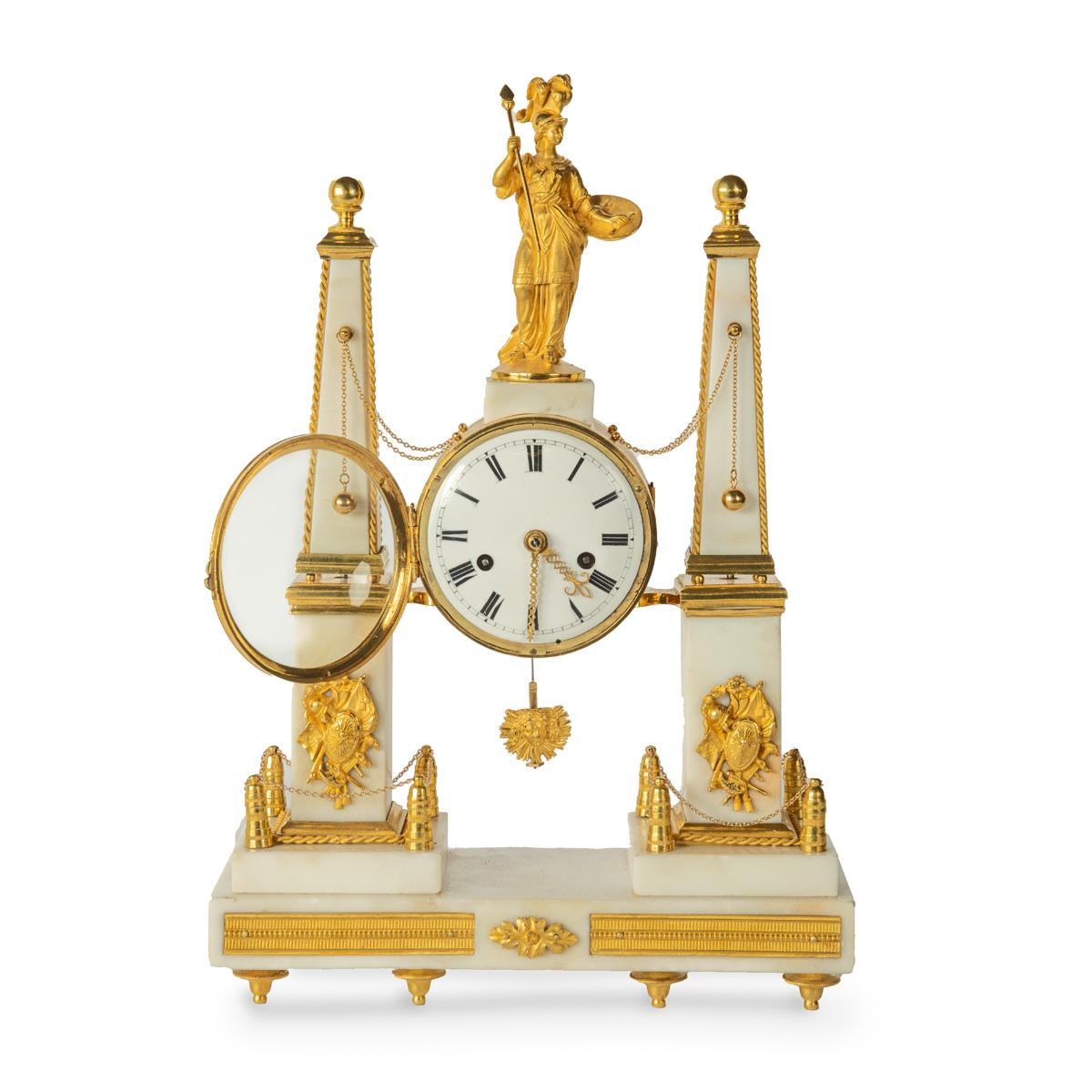 A late Louis XVI marble and ormolu portico clock, comprising a central drum-shaped clock with a sunburst pendulum, surmounted by the gilded figure of Athena wearing armour with a plumed helmet and Gorgon’s head shield, suspended between two obelisks