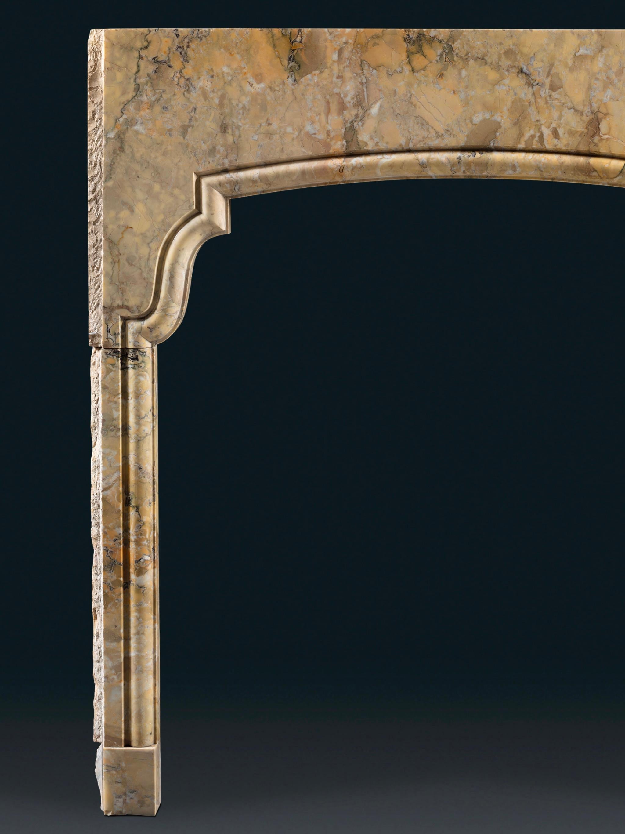 The form is simple and highly elegant, slim jambs leading up to a bowed header by way of serpentine shoulders. Subtly evoking the exotic, the form of this chimneypiece makes the most of the Sienna from which it is carved.

Height 53⅛in (135cm) width