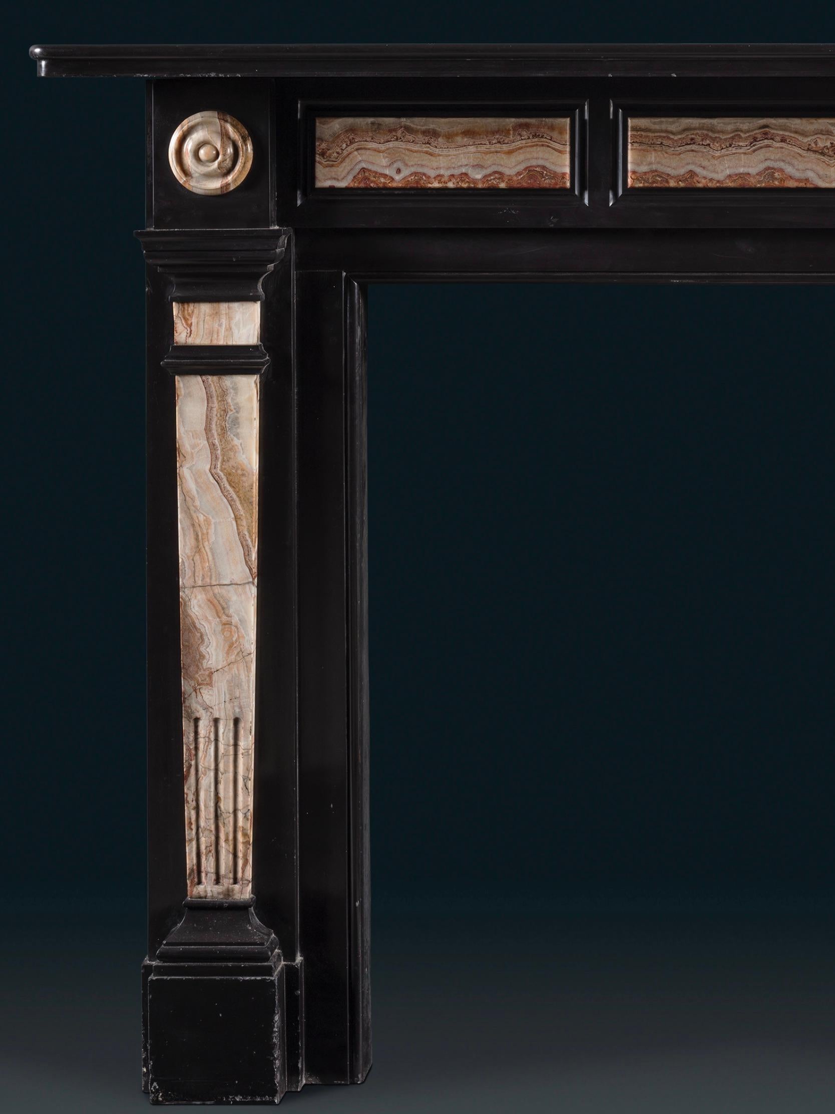 A Late Regency Chimneypiece Carved from Belgium Black Marble with Specimen Onyx Fielded Panels, Pedestal Jambs and Bull's Eyes

The overall form is pleasing, the contrasting onyx striking against the Belgium black.

Height 51⅝in (131cm) width 64⅝in