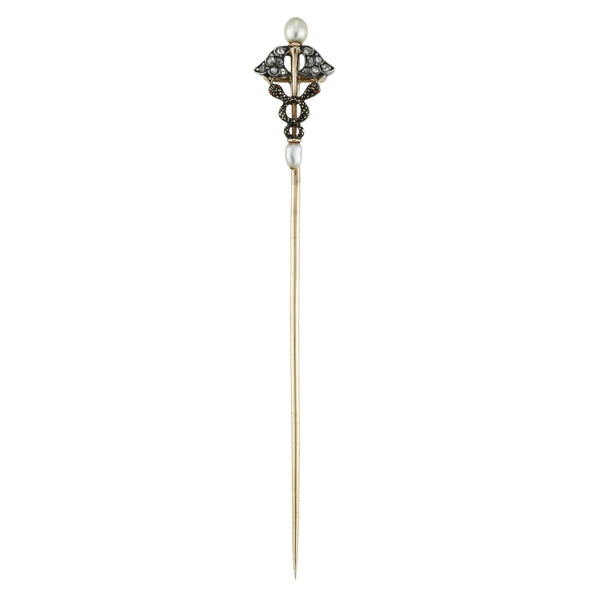 A late Victorian caduceus pearl and diamond stickpin, the two entwined snakes with black enamel decorations, the wings encrusted with rose-cut diamonds, the staff terminating to a pearl on each end, mounted in silver and gold, with gold pin, circa