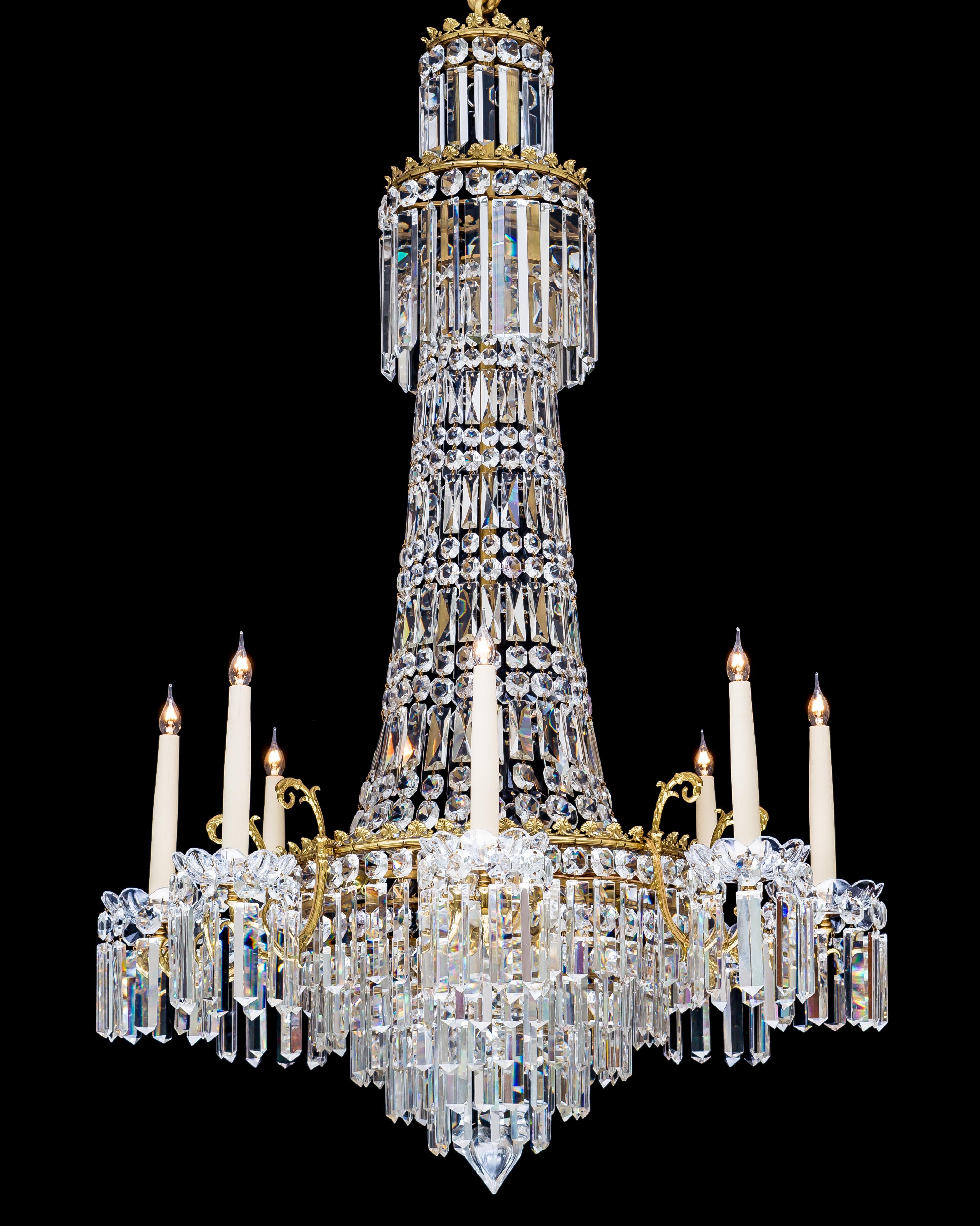 A eight-light cut glass and gilt mounted chandelier of classic tent and waterfall design the stem consisting of two drop hung rings with decorative banding and a tent of drops cascading to the main ring, the main ring supporting eight candle arms