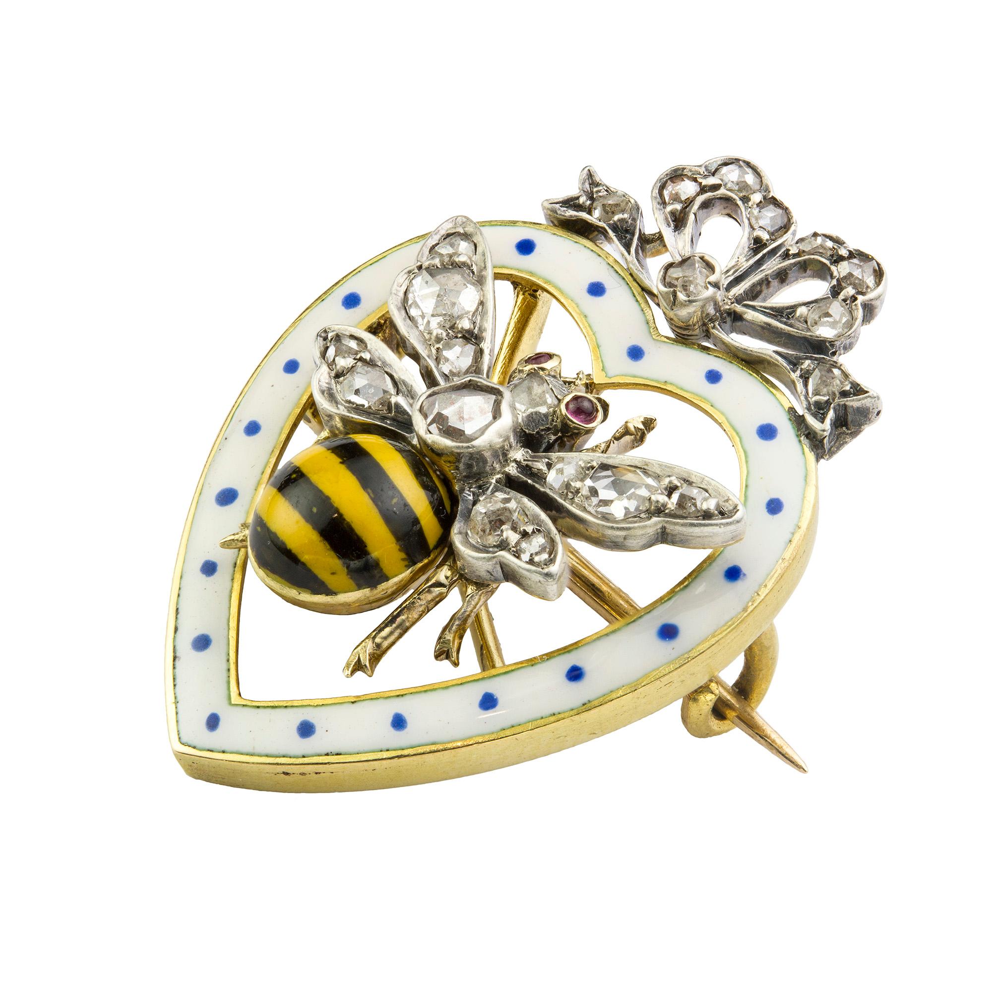 A late Victorian enamel and diamond bee brooch, the thorax and wings set with rose-cut diamonds, the abdomen with black and yellow enamel stripes, the eyes set with cabochon-cut rubes, surrounded by a heart-shaped white and blue enamelled frame with