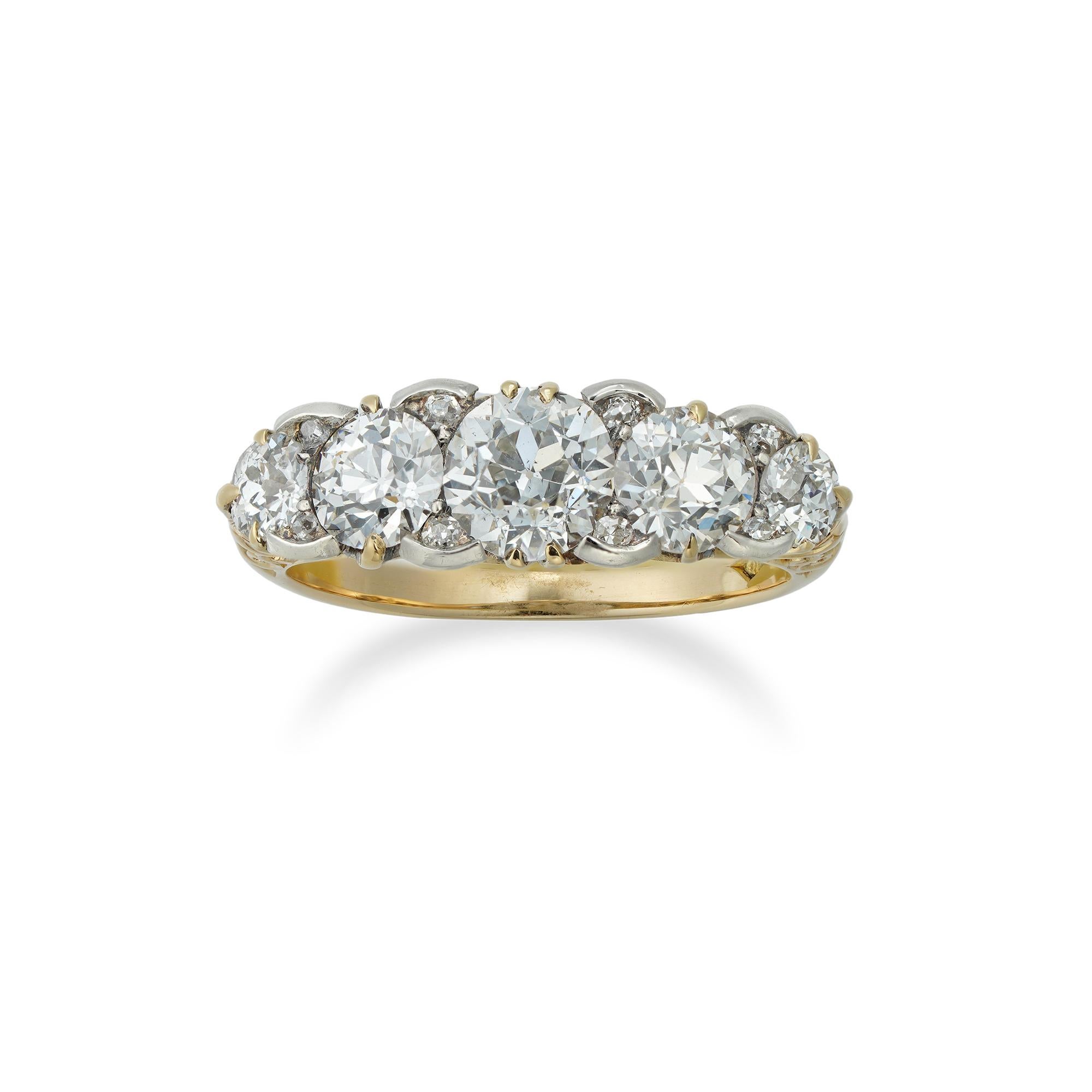 A late Victorian five stone diamond ring, the five old European-cut diamonds graduating from the centre and estimated to weigh 1.95 carats in total, embellished with rose-cut diamonds in-between, mounted in silver to a yellow gold mount with scroll