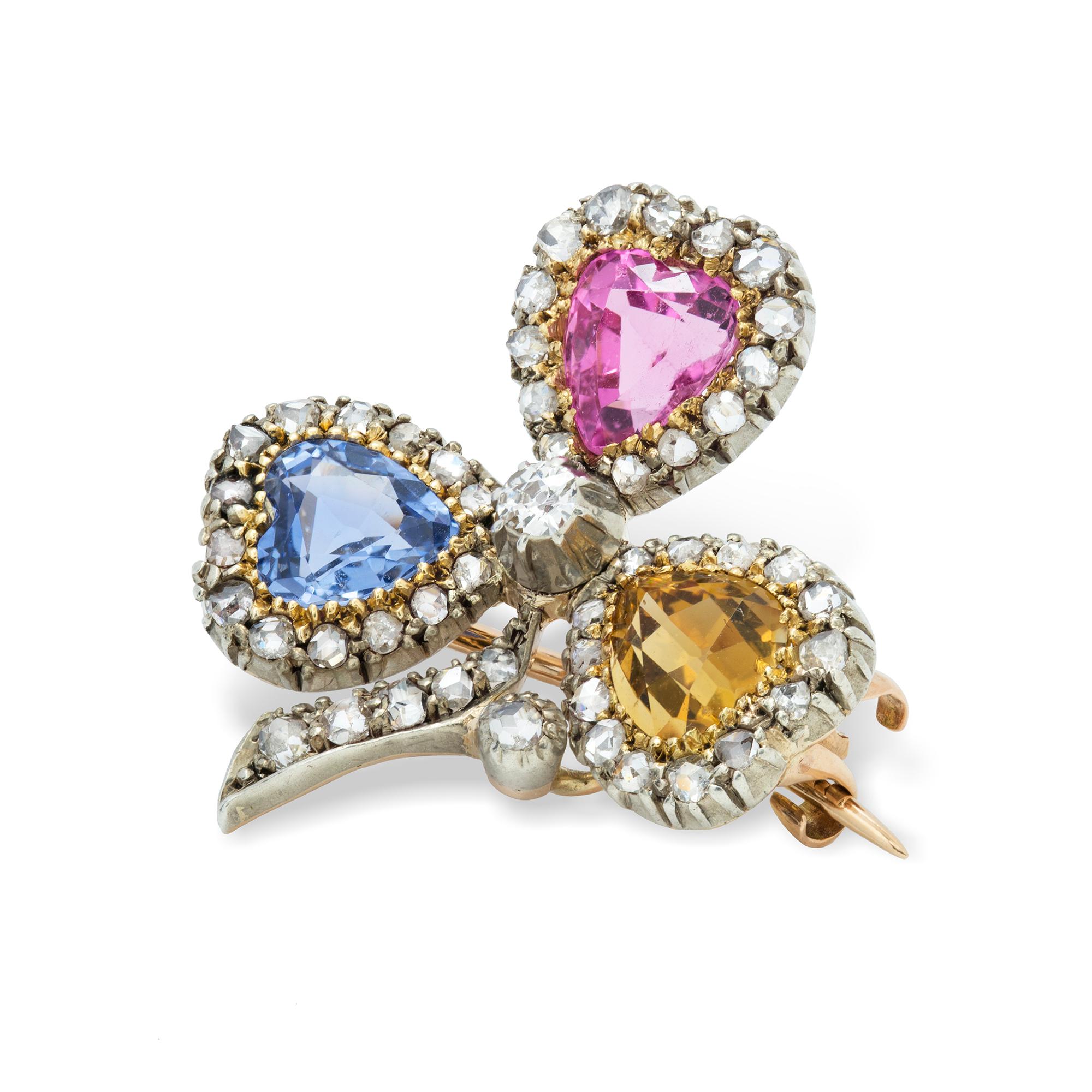 A late Victorian multi-colour gem and diamond clover leaf brooch, the three leaves each set with a heart-shaped faceted stone, one pale blue sapphire, one pink tourmaline and one golden citrine, each set to the centre of a cluster surround of