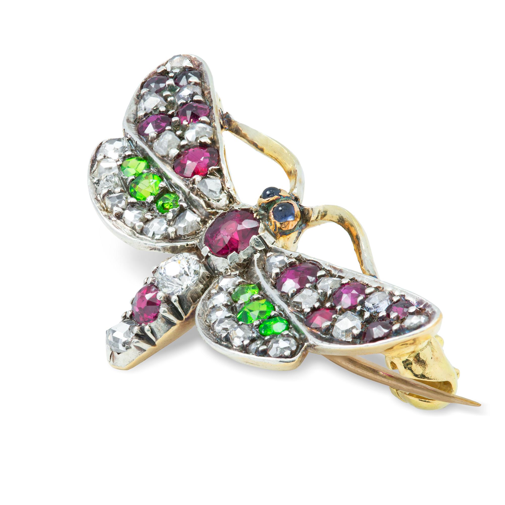 A late Victorian multi-gem butterfly brooch, the wings and body encrusted with old-cut and rose-cut diamonds, highlighted with demantoid garnets, and rubies, with cabochon-cut sapphire eyes, set in silver to a yellow gold mount and brooch fitting,