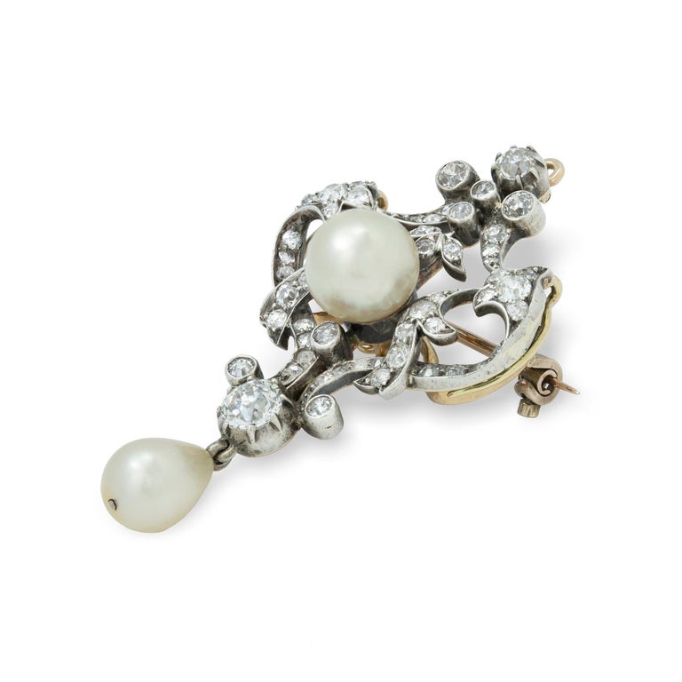 A late Victorian pearl and diamond brooch/pendant, centrally-set with a cream pearl measuring approximately 8.7 mm in diameter, to a diamond-set scroll openwork designed surmount, terminating to an old European-cut diamond weighing approximately 0.4