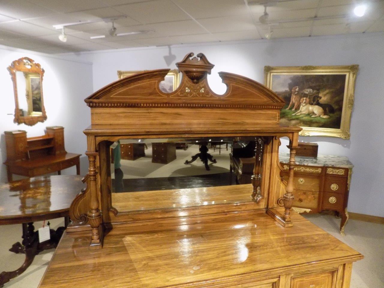 A late Victorian period walnut and marquetry inlaid antique side cabinet. The upper section having a broken swan neck cornice with marquetry inlaid detail moulding above the shaped bevelled mirror and with finely turned column supports. The lower