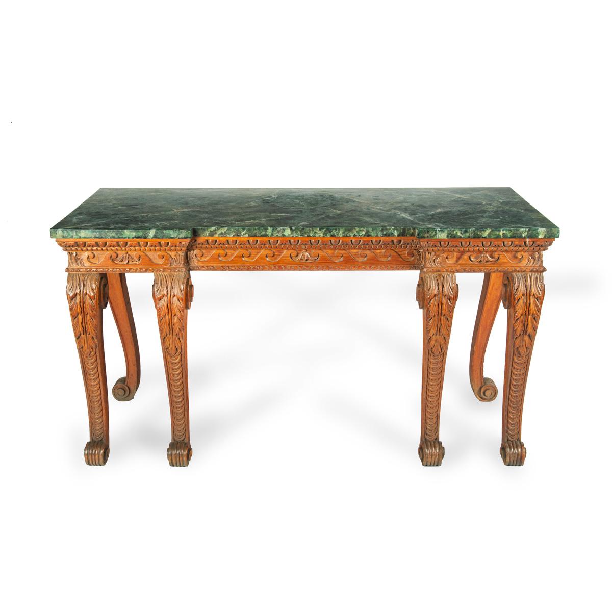 
A late Victorian pitch pine console table after Linnell, the rectangular top set upon a frieze carved with Vitruvian scrolls and surmounted by a painted faux marble top, all raised upon six powerful cabriole scroll legs carved with acanthus leaves