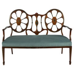 Antique A late Victorian satinwood wheel back settee in the Chippendale style